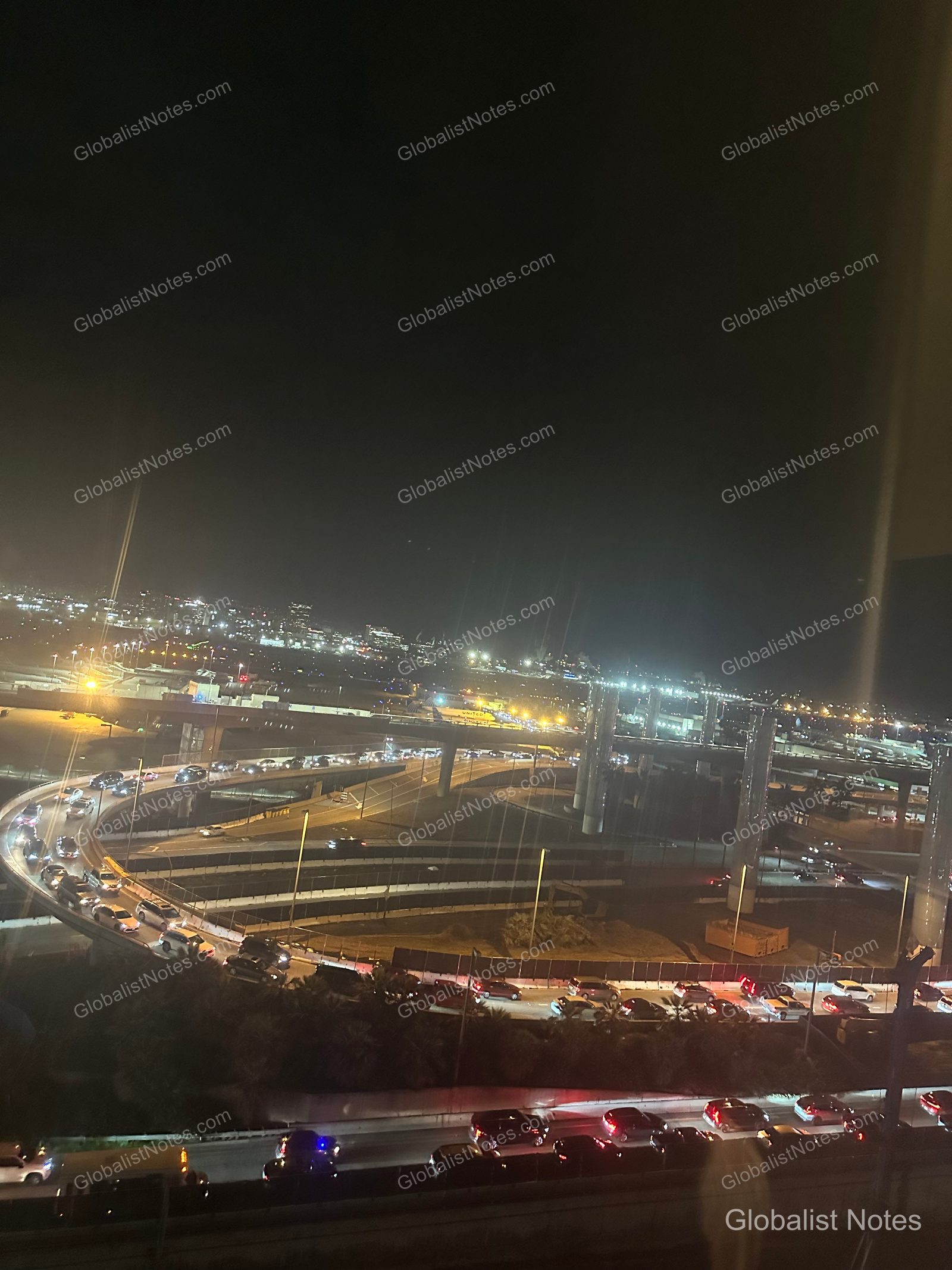 Night view from a Hyatt Regency Los Angeles International Airport guest room, showing the airport approach and highway illuminated by the headlights of moving traffic and streetlights against the dark night sky.