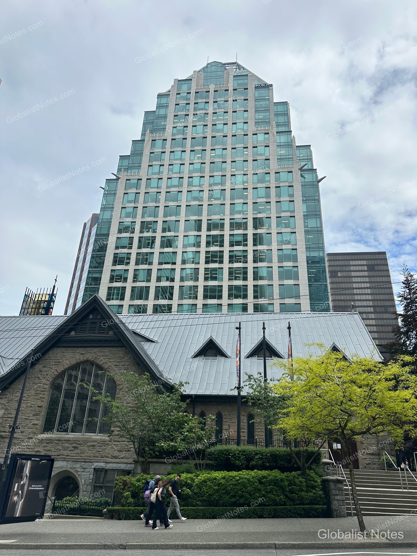The high-rise glass facade of Hyatt Regency Vancouver towers over a historic stone church with a gabled roof. Pedestrians walk along the sidewalk in front, highlighting the contrast between the modern hotel and the historic architecture under a clear sky.