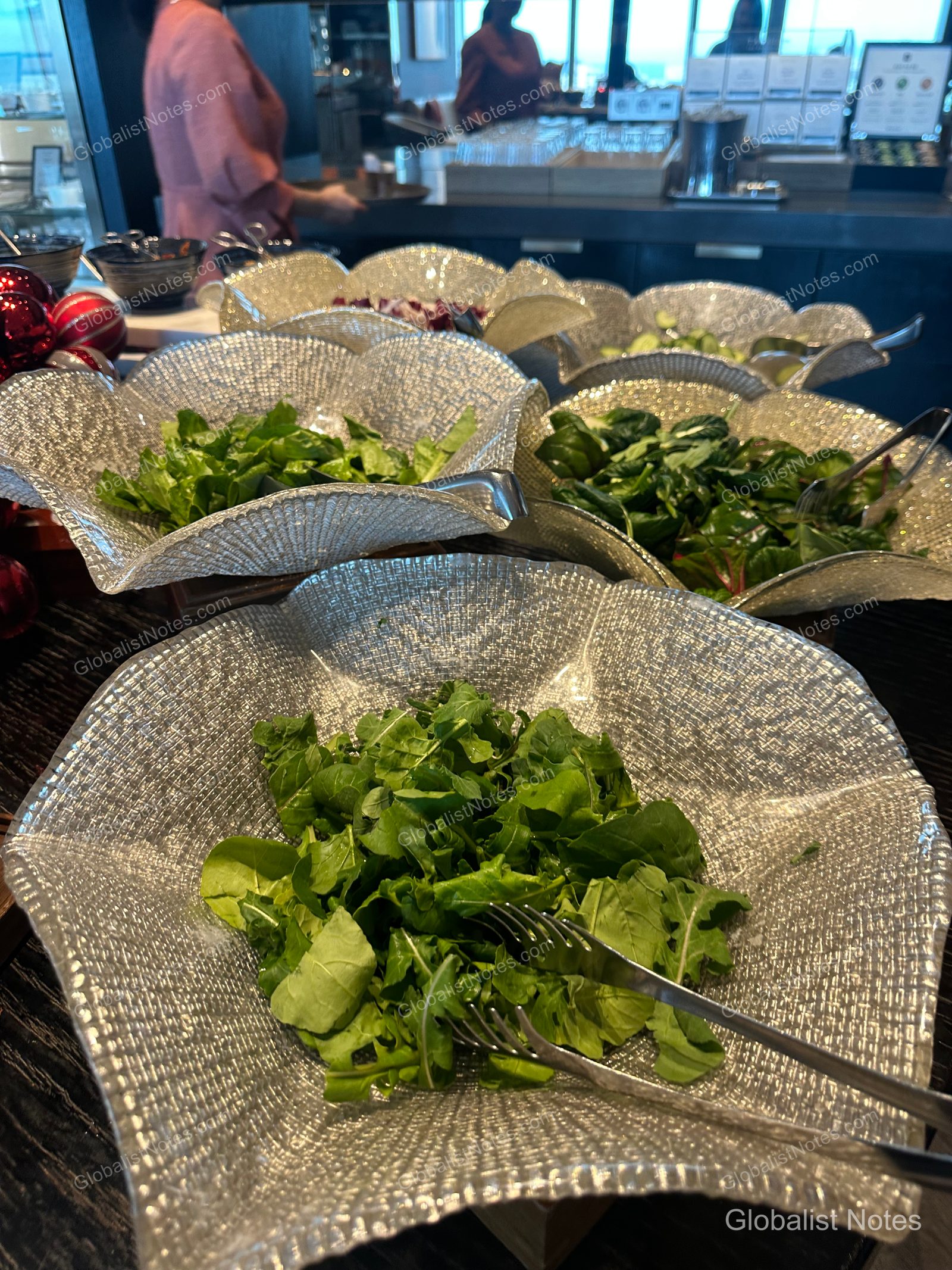 Salad station at the Grand Hyatt Jeju breakfast buffet, featuring fresh arugula and assorted leafy greens displayed in textured, petal-shaped glass bowls with serving tongs.