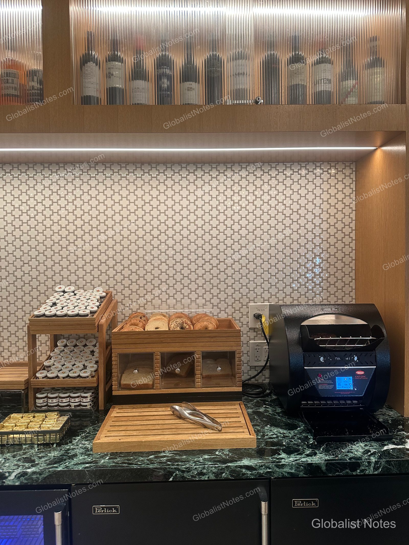 Hyatt Regency Irvine 早餐自助區，綠色大理石檯面上擺放著木製托盤，內有貝果、吐司及小型果醬罐，右側為黑色烤麵包機，背景可見幾何圖案磁磚牆與陳列酒瓶的櫥櫃。