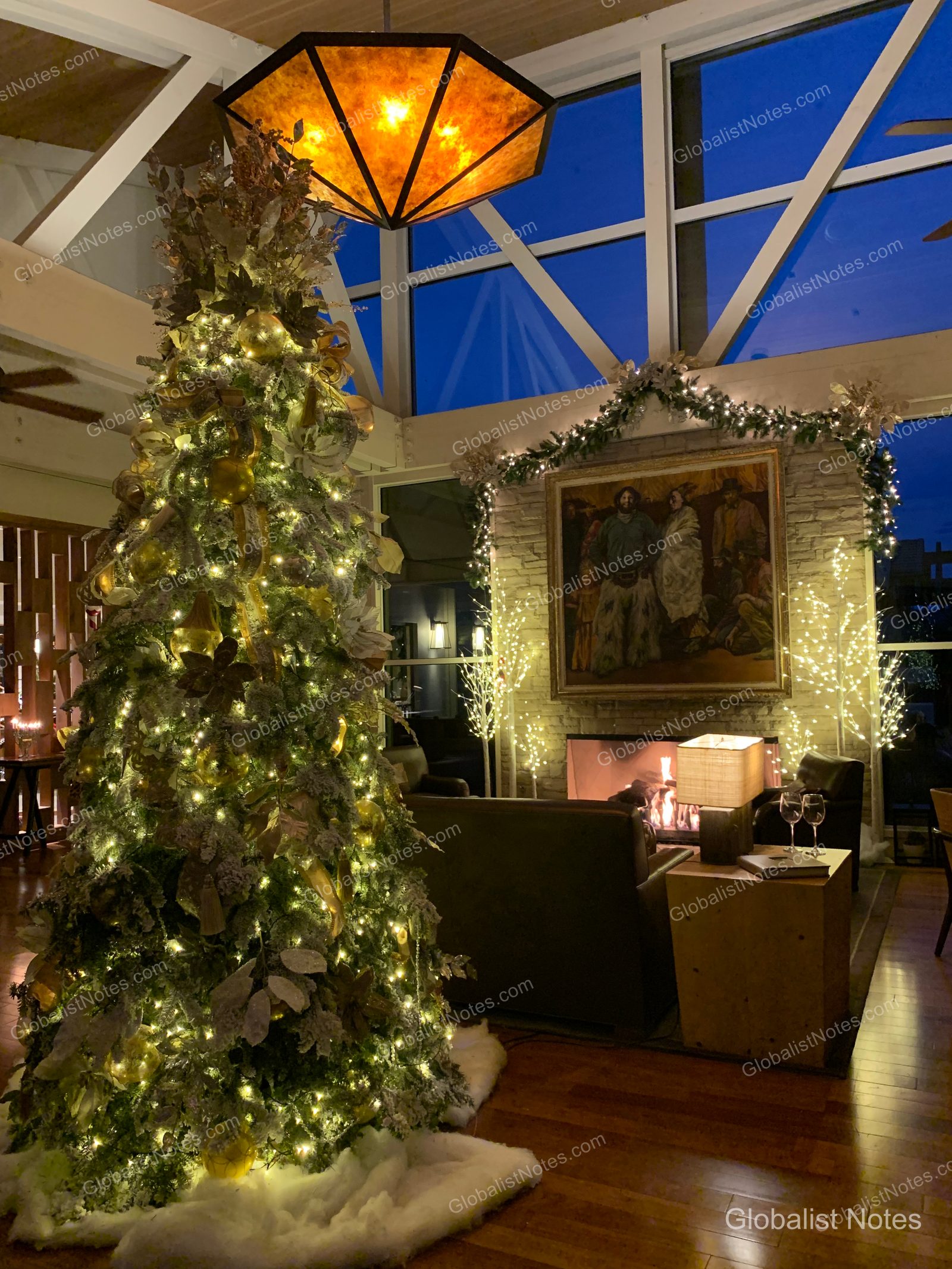 Carmel Valley Ranchのロビー。大きなクリスマスツリーと暖炉が配された居心地の良いラウンジエリアです。高い天井と大きな窓からは夕暮れ時の空が広がり、温かみのある照明が年末の雰囲気を引き立てています。