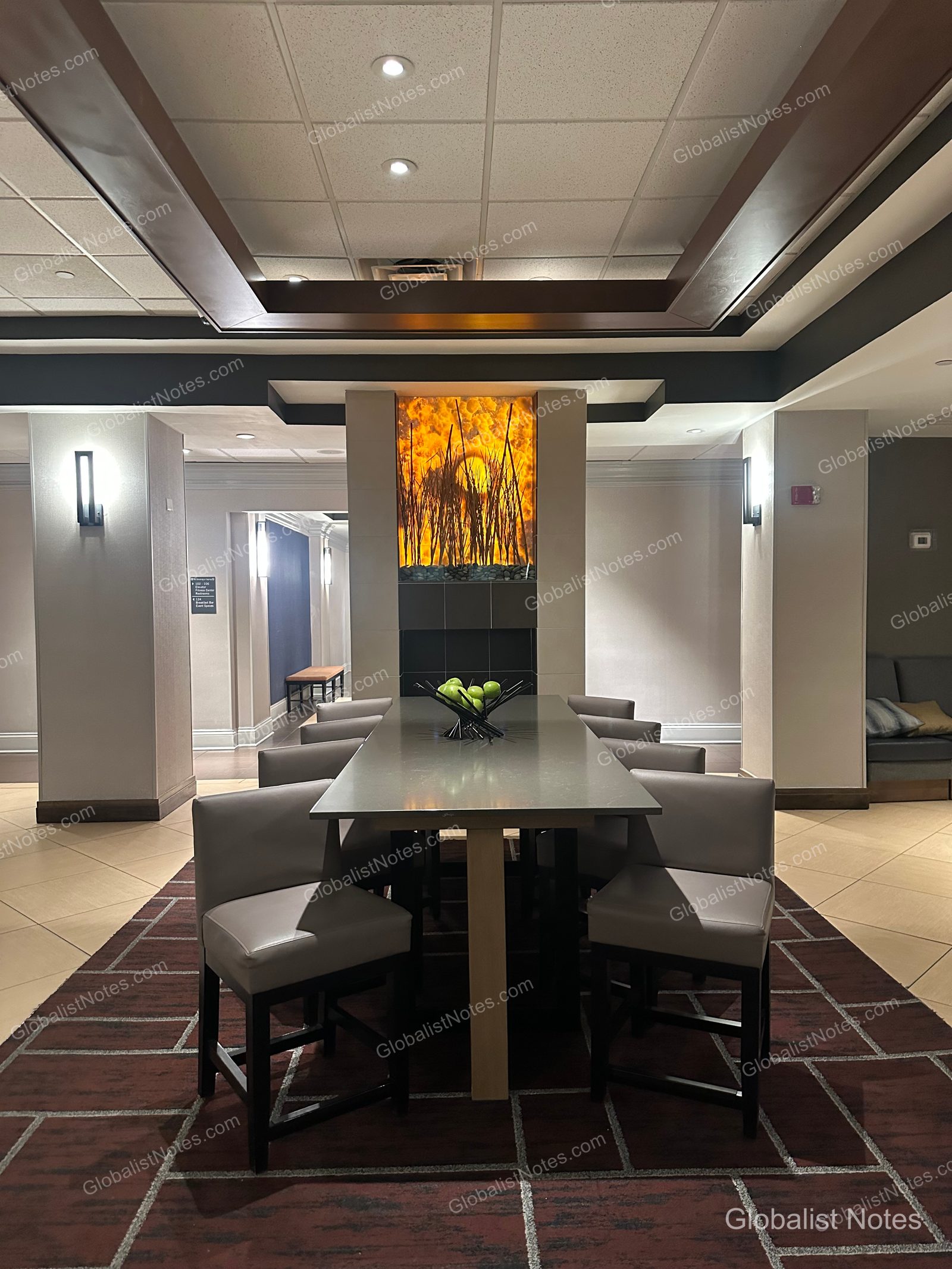 El Paso 機場 Hyatt Place 大廳公共區，中央設有長桌與灰色座椅，後方牆面裝飾著發光藝術裝置，地面鋪設深棕色幾何圖案地毯。