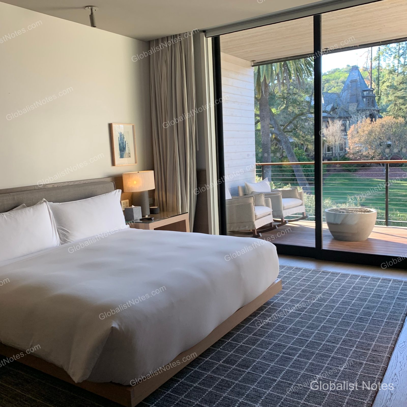 Interior view of a 2 Queen Bed Vineyard View Balcony room at Alila Napa Valley, featuring white bedding, a patterned rug, and floor-to-ceiling windows overlooking the outdoor terrace and vineyard.