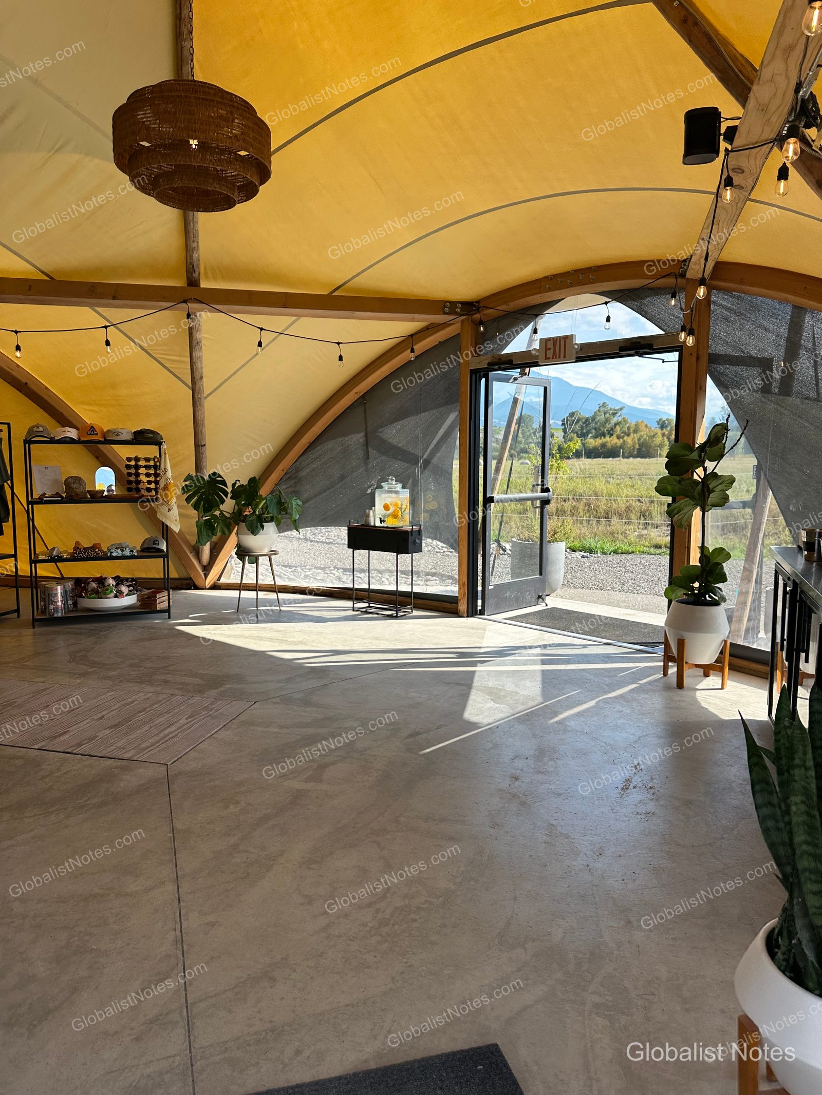 Under Canvas North Yellowstoneのロビー内部。コンクリート床にグッズ棚や観葉植物、ウォーターサーバーが置かれ、開放的な入り口からはパラダイスバレーの景色が望めます。