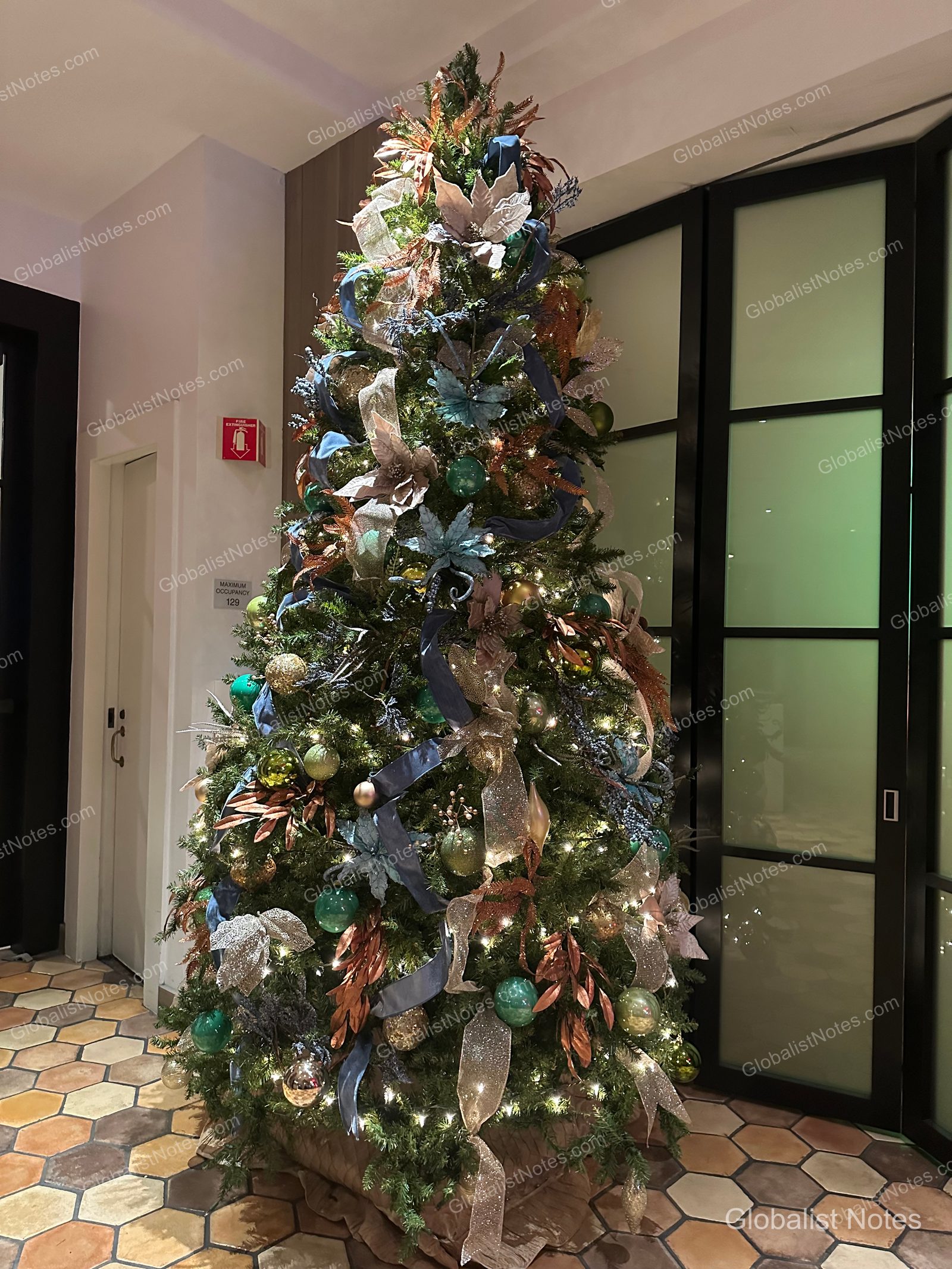 Hyatt Regency La Jolla 大廳內的聖誕樹，掛滿綠色、金色與藍色的裝飾球、緞帶及花卉，底座設於六角形磁磚地板上。
