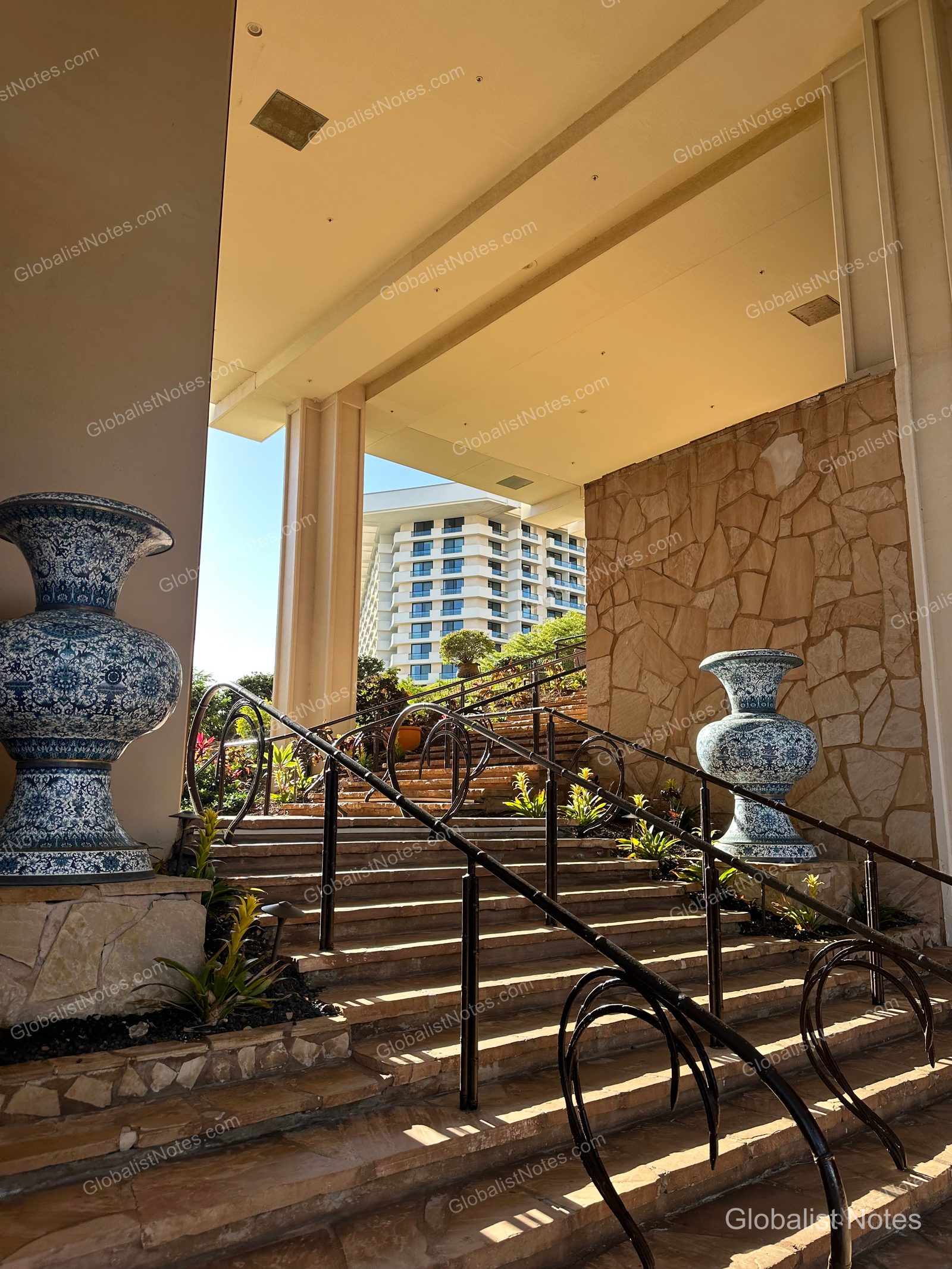 Outdoor stairs at Hyatt Regency Maui Resort and Spa in Lahaina, Hawaii. Large blue-patterned ceramic planters line both sides, with the resort exterior and blue sky visible beyond the stone steps.