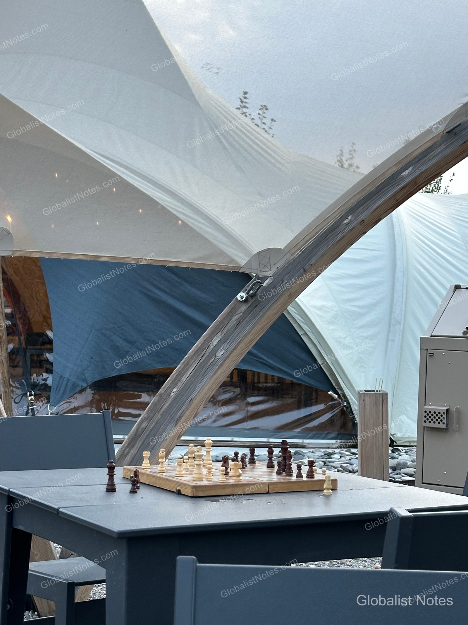Under Canvas North Yellowstoneの屋外スペースに置かれたチェス盤。背後には日よけの下に並ぶ大型のキャンバステントが見えます。