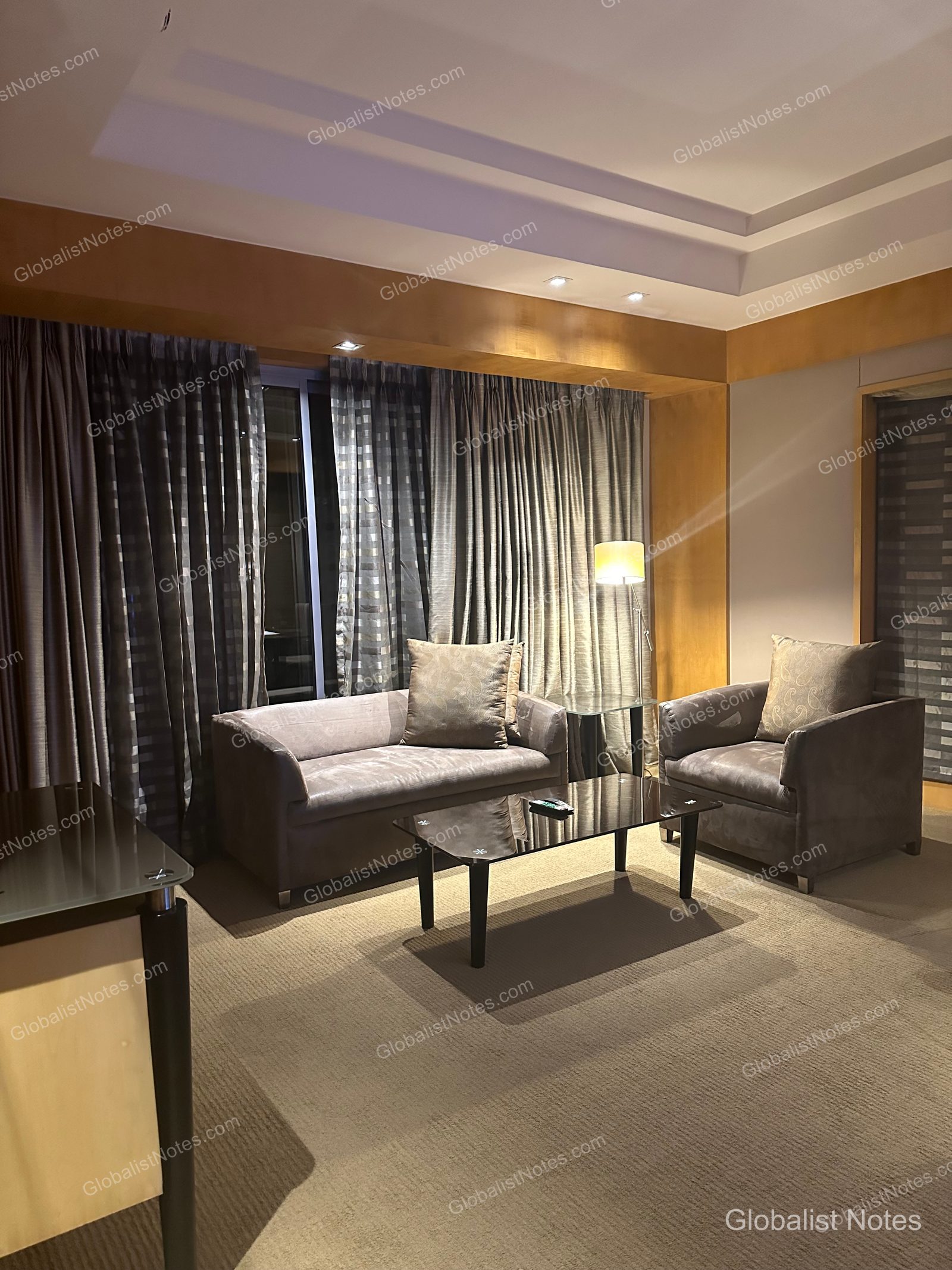 Living area of the Veranda Suite King at Grand Hyatt Mumbai Hotel and Residences, featuring a neutral-toned sofa, an armchair, a glass-topped coffee table, and ambient lighting.