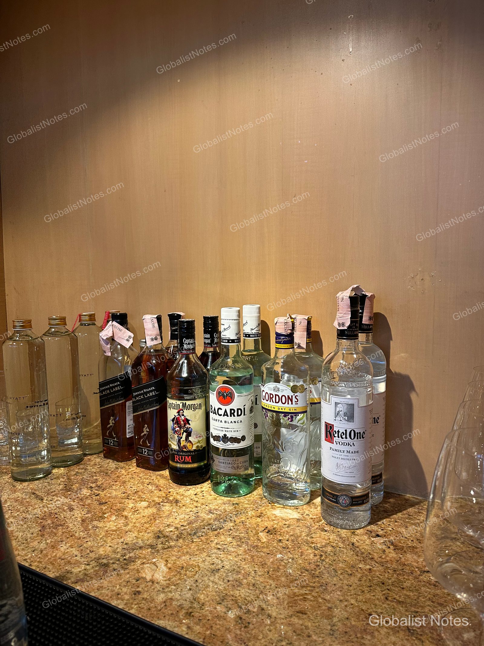 A selection of spirits on a marble counter in the Grand Hyatt Mumbai lounge, including Johnnie Walker Black Label, Captain Morgan, Bacardi, Gordon's, and Ketel One.