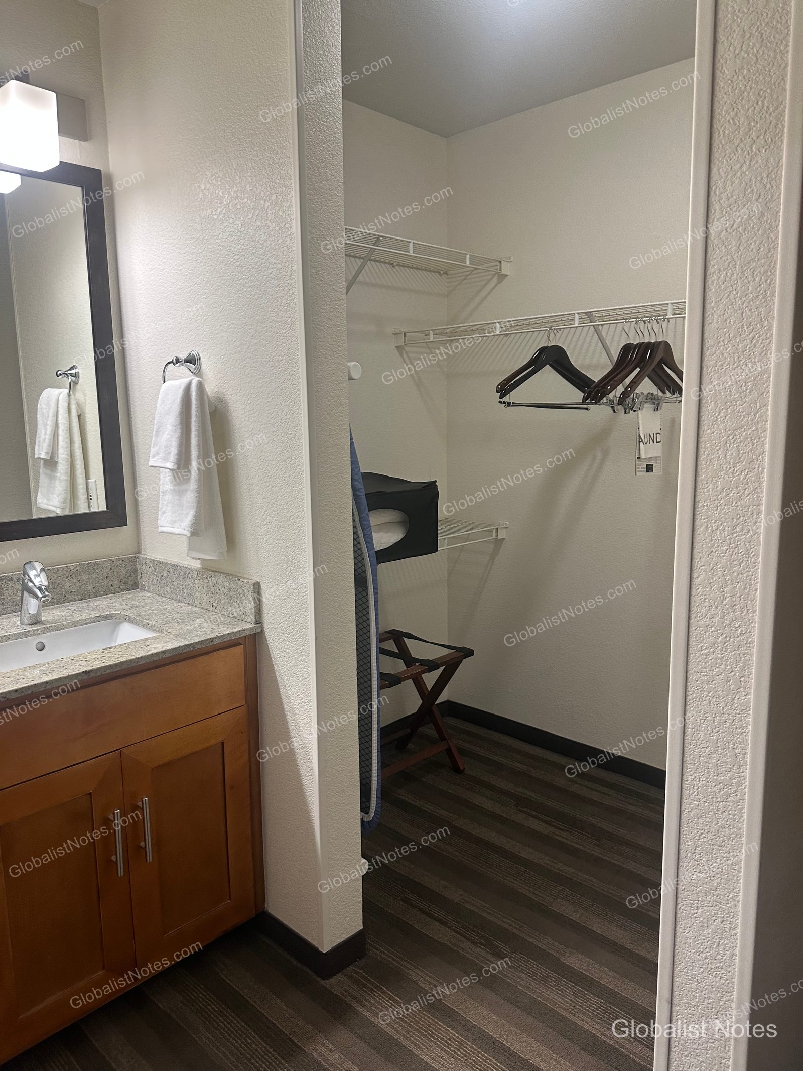 Hyatt House Scottsdale/Old Townのワンベッドルームスイート、バスルーム横のウォークインクローゼット。アイロン台、バゲージラック、ハンガーラックが備わっています。