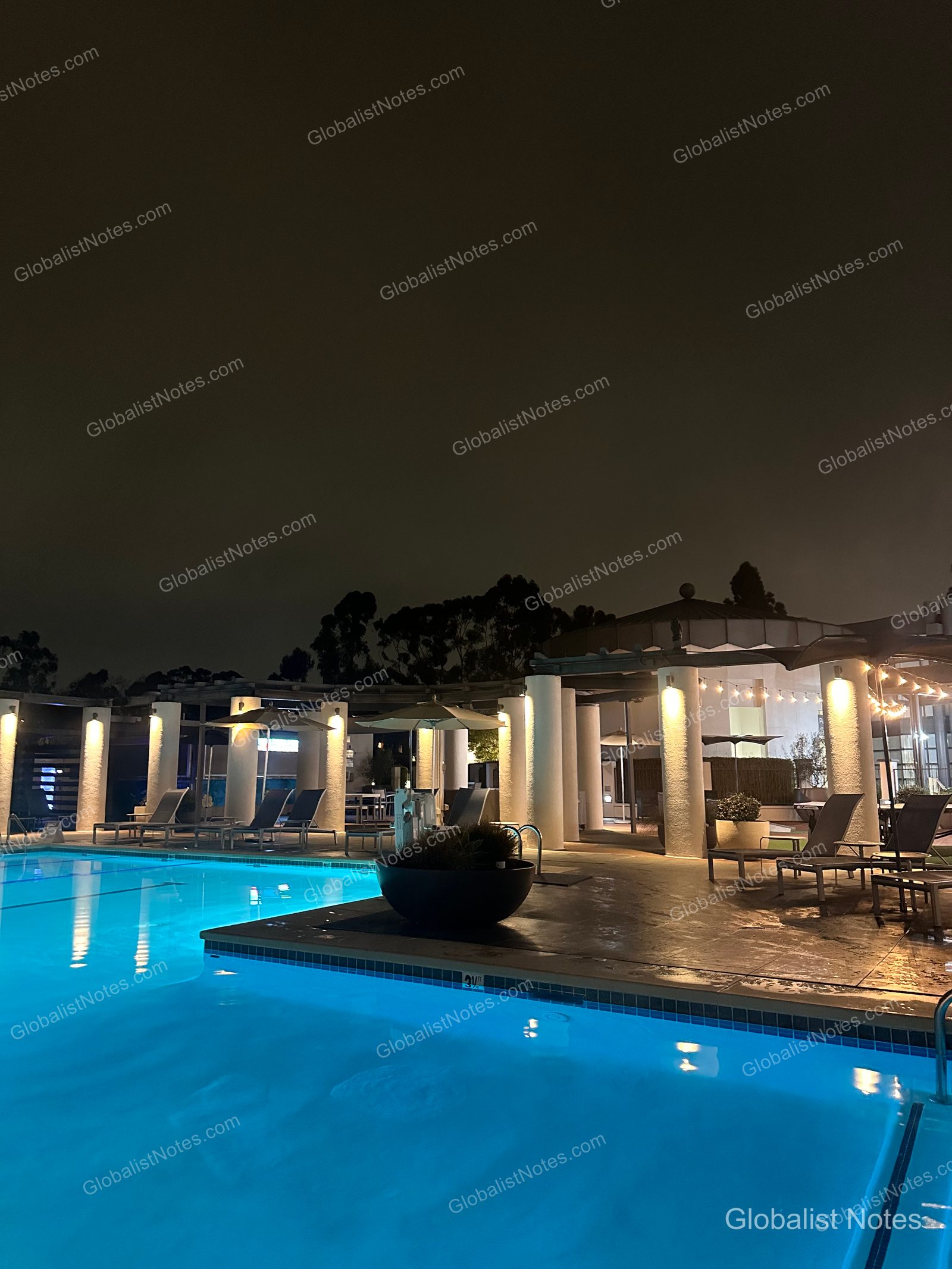 San Diego Hyatt Regency La Jolla at Aventine 戶外泳池夜景。夜色下，打著燈光的柱子與池畔躺椅，與湛藍的池水形成對比。