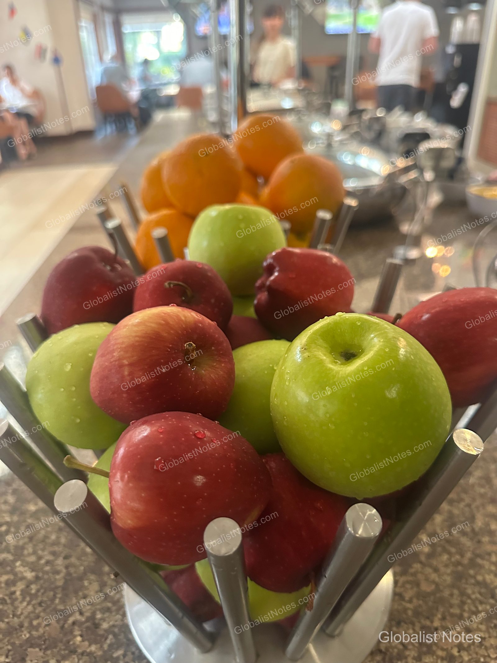 Hyatt House Scottsdale/Old Townの朝食ビュッフェ。金属製のバスケットに盛られたリンゴやオレンジなどの新鮮なフルーツ。