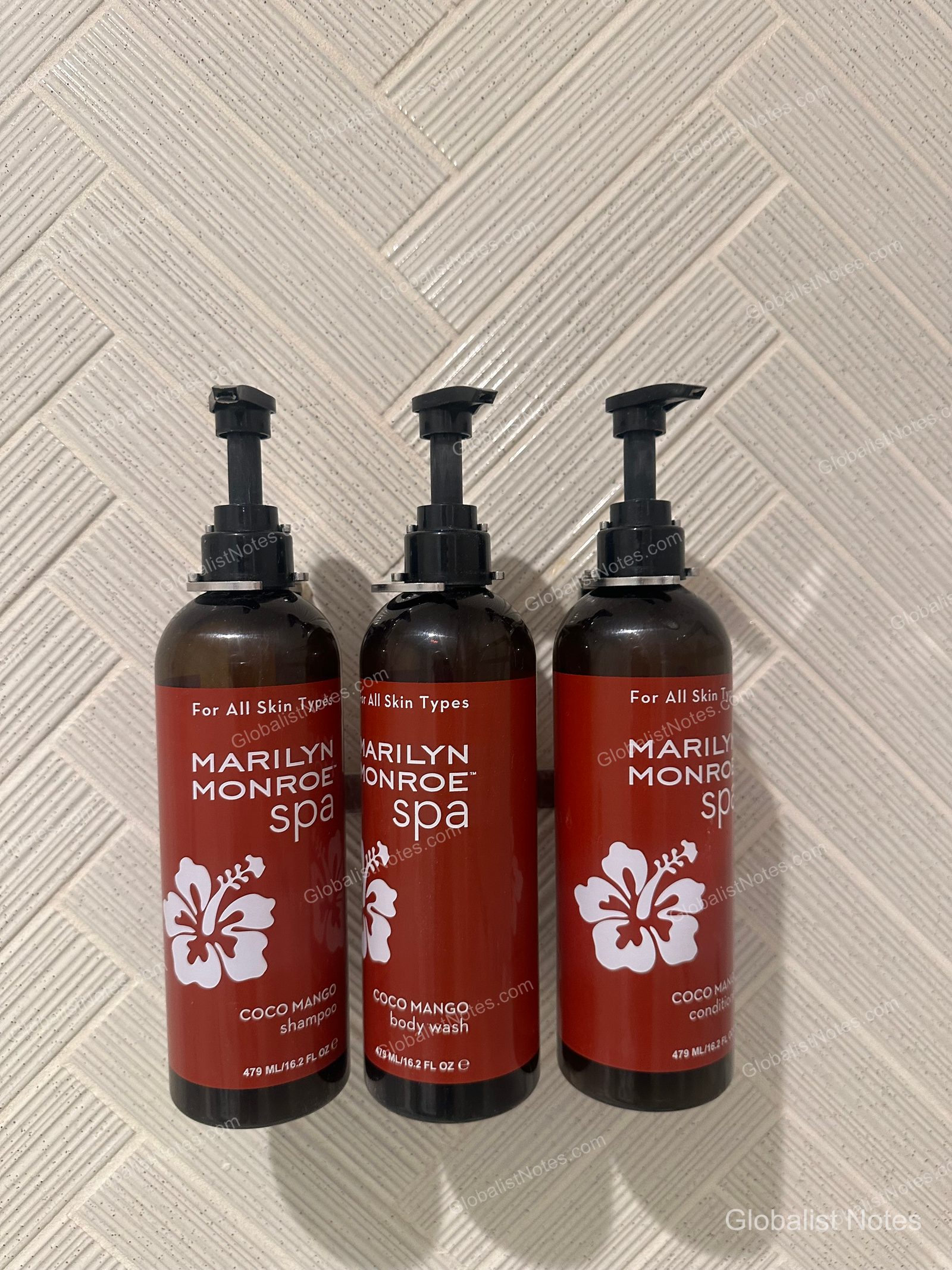 Three pump-style bottles of Coco Mango shampoo, body wash, and conditioner from Marilyn Monroe Spas mounted on the bathroom wall at Hyatt Regency Maui Resort and Spa.