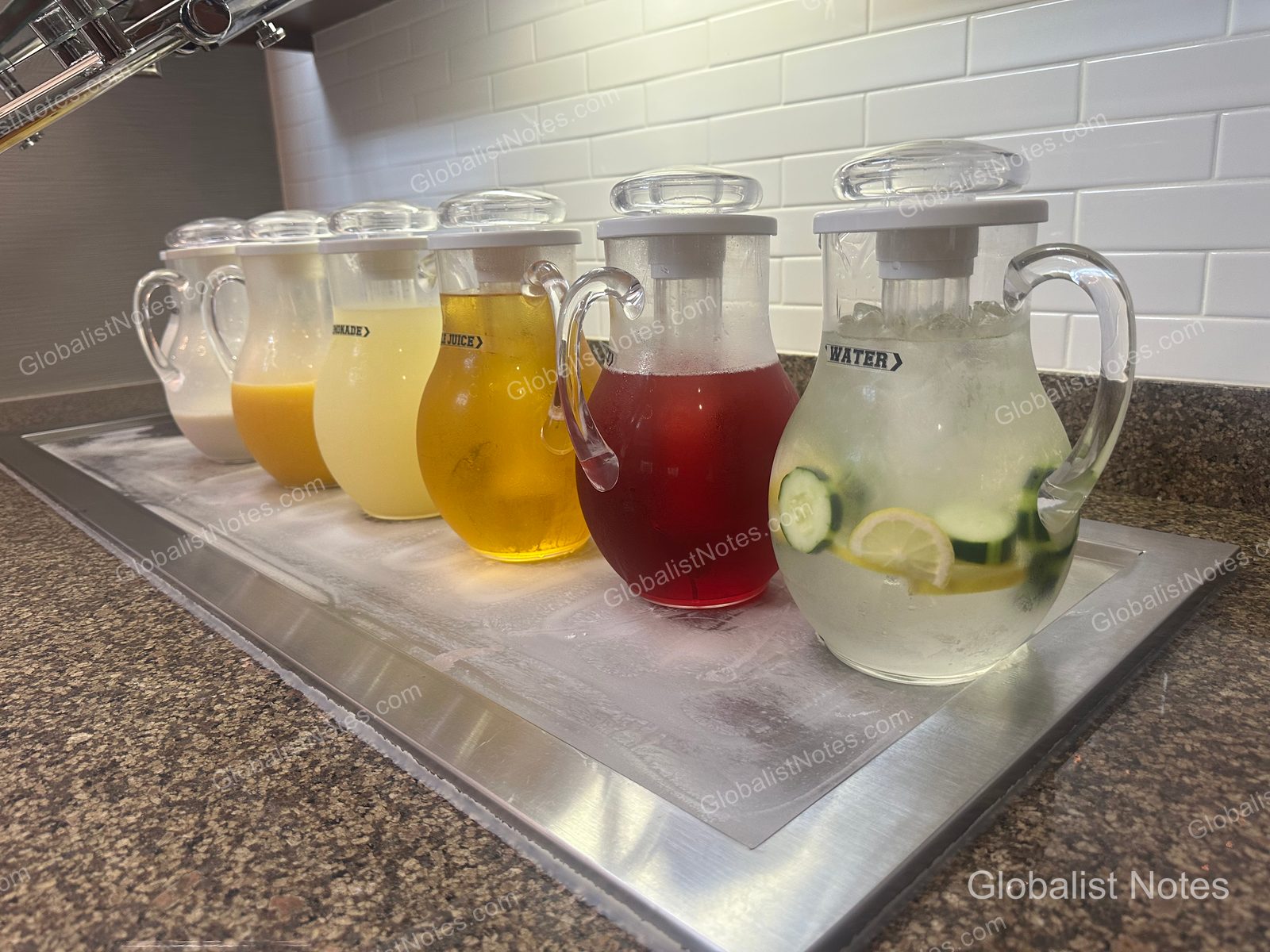 Hyatt House Scottsdale Old Townの朝食コーナー。ステンレス製の台に、牛乳、オレンジジュース、レモネード、リンゴジュース、クランベリージュース、そしてキュウリとレモン入りの冷水が入ったガラスピッチャーが並んでいる。