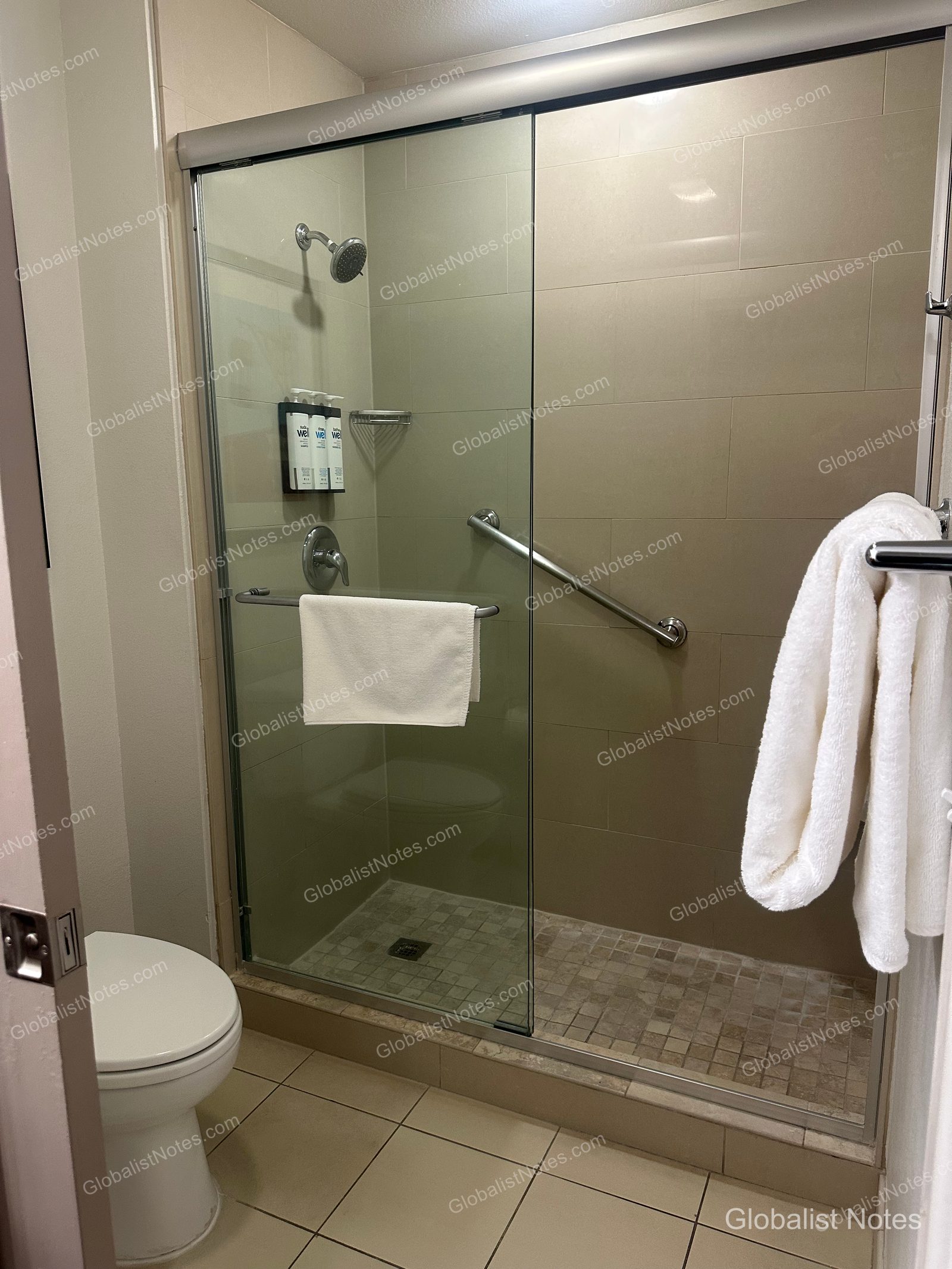 Hyatt House Scottsdale Old Townの1ベッドルームスイートのバスルーム。ガラス戸付きのシャワーブースには手すりが備わり、壁面には詰め替え式のアメニティとタオルが整然と配置されている。
