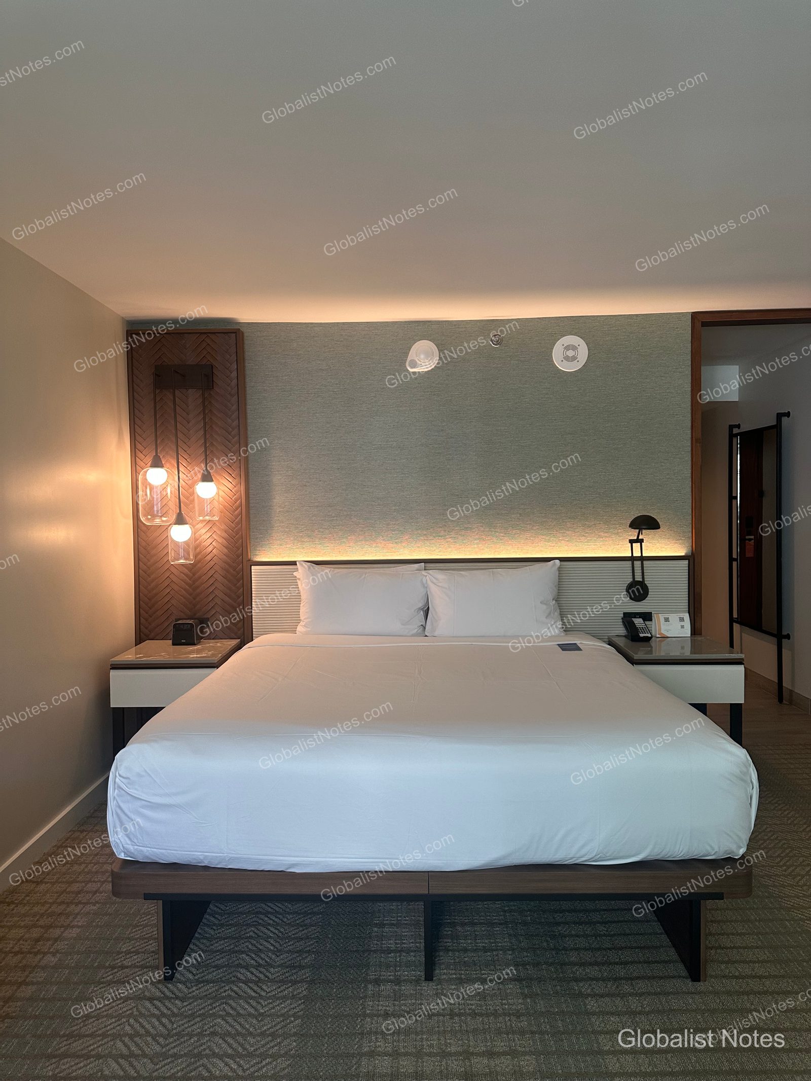Interior view of a standard king room at Hyatt Regency Maui Resort and Spa. A king bed with white linens is centered in the room, flanked by nightstands and lamps, with soft accent lighting behind the headboard.