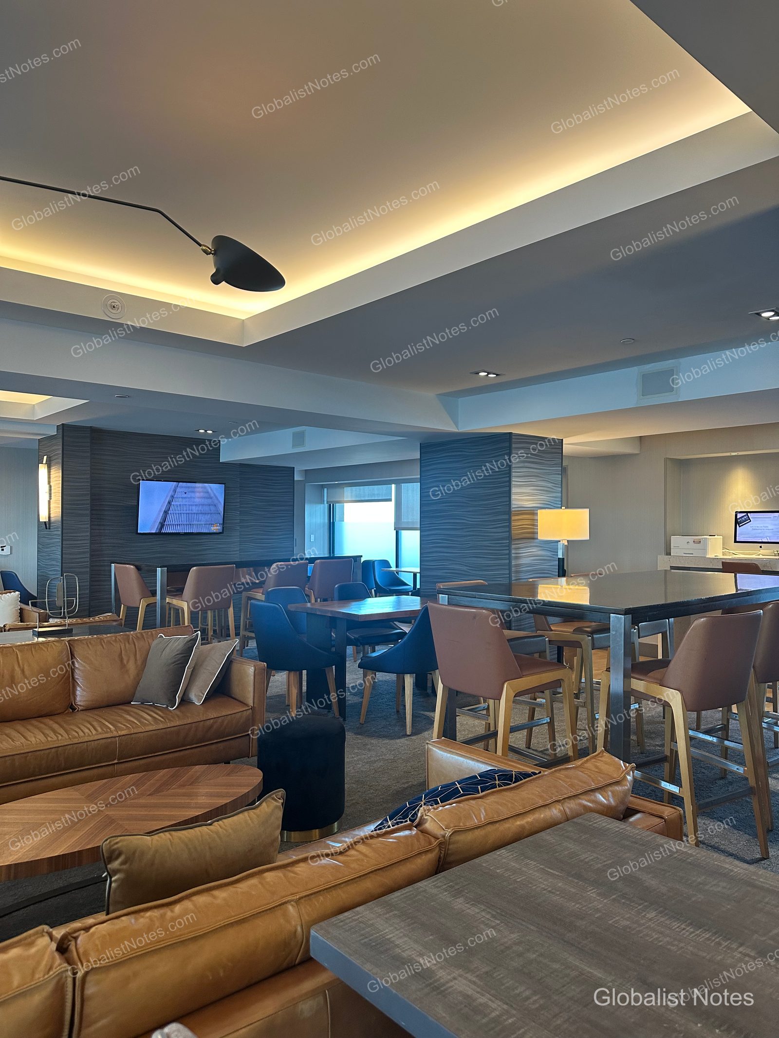 Manchester Grand Hyatt San Diego 貴賓廳內部，空間寬敞，配置棕色皮革沙發與藍色座椅，牆面設有電視，並搭配高腳桌椅與間接照明。