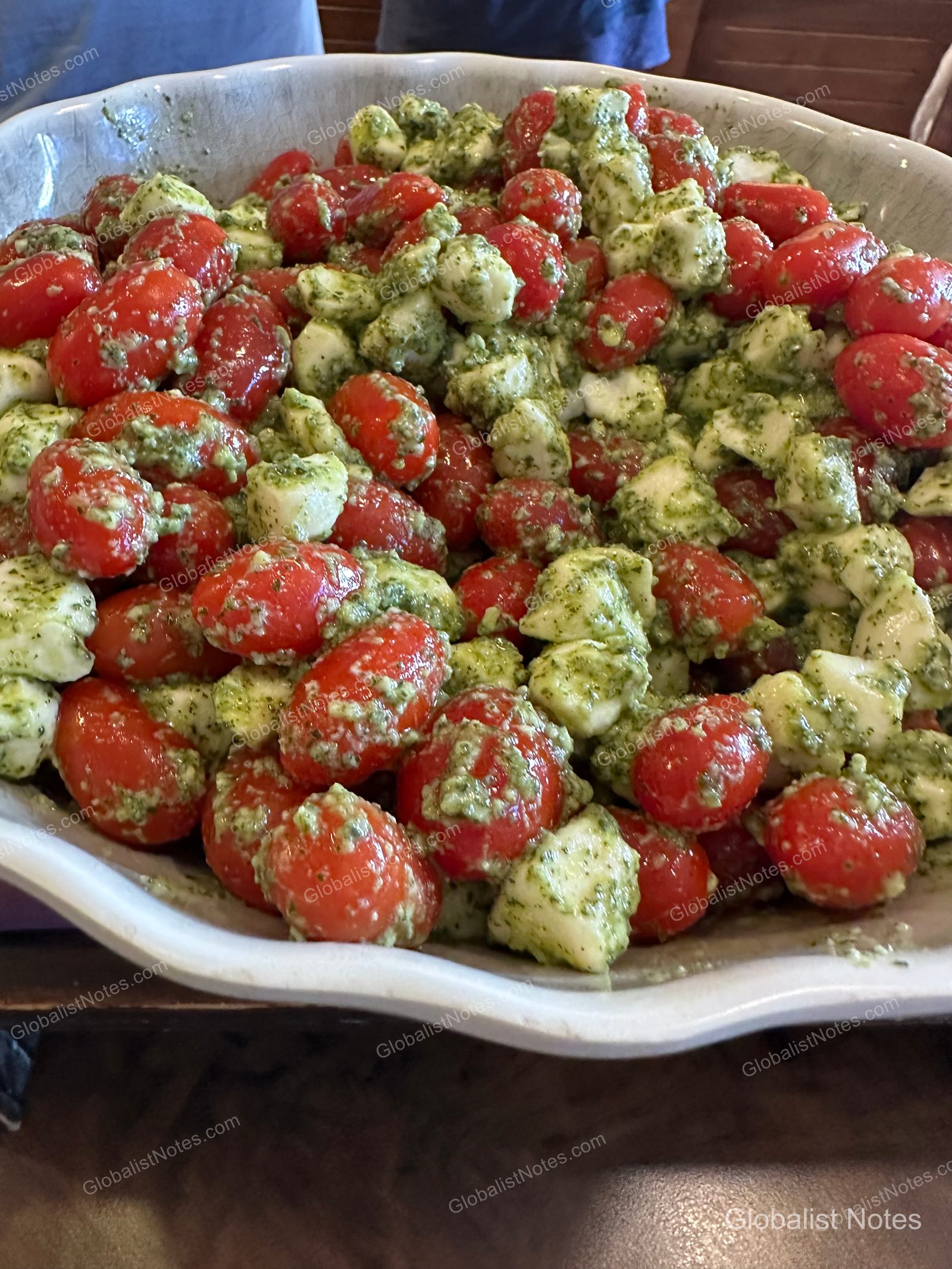 Caprese salad in a large white bowl at the breakfast buffet at Hyatt Regency Maui Resort and Spa. The dish features cherry tomatoes and bite-sized mozzarella cheese tossed in basil pesto.