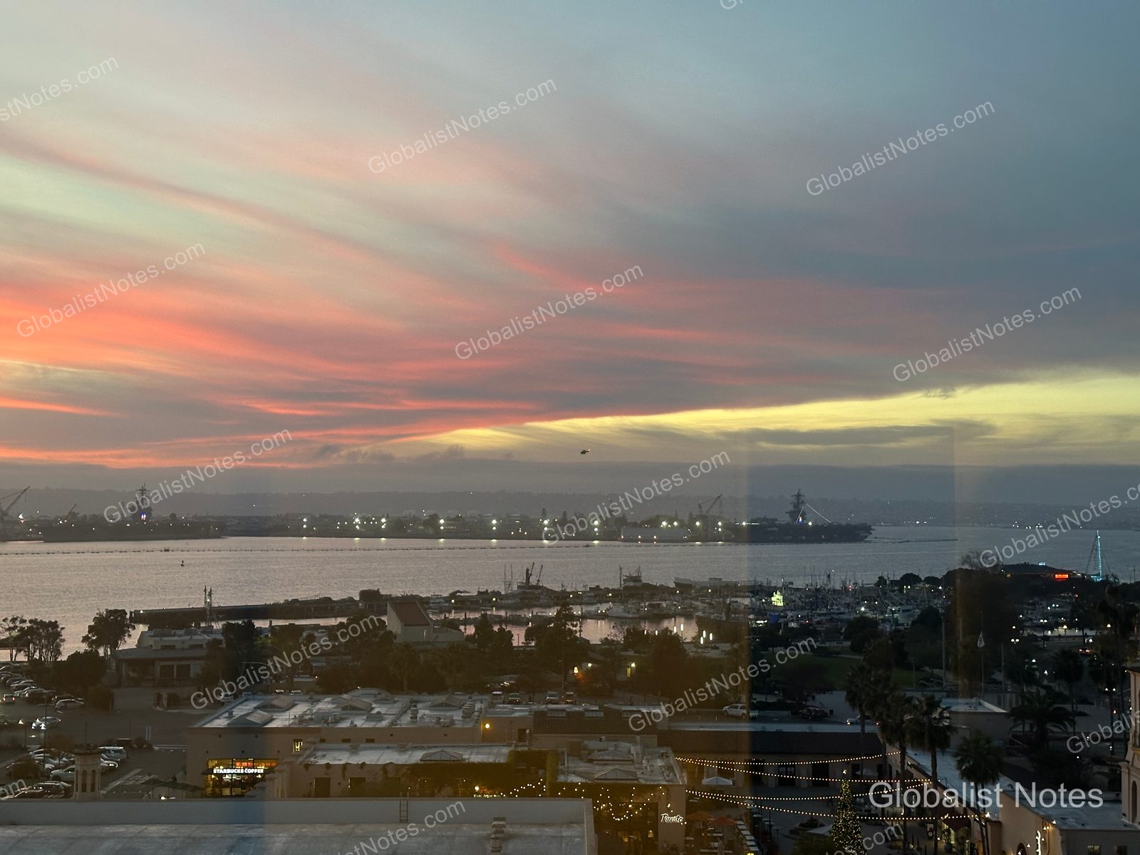 從 Manchester Grand Hyatt San Diego 客房望向聖地牙哥港口的夕陽，粉橘色天空映襯著海面、停泊船隻與岸邊建築的夜景。