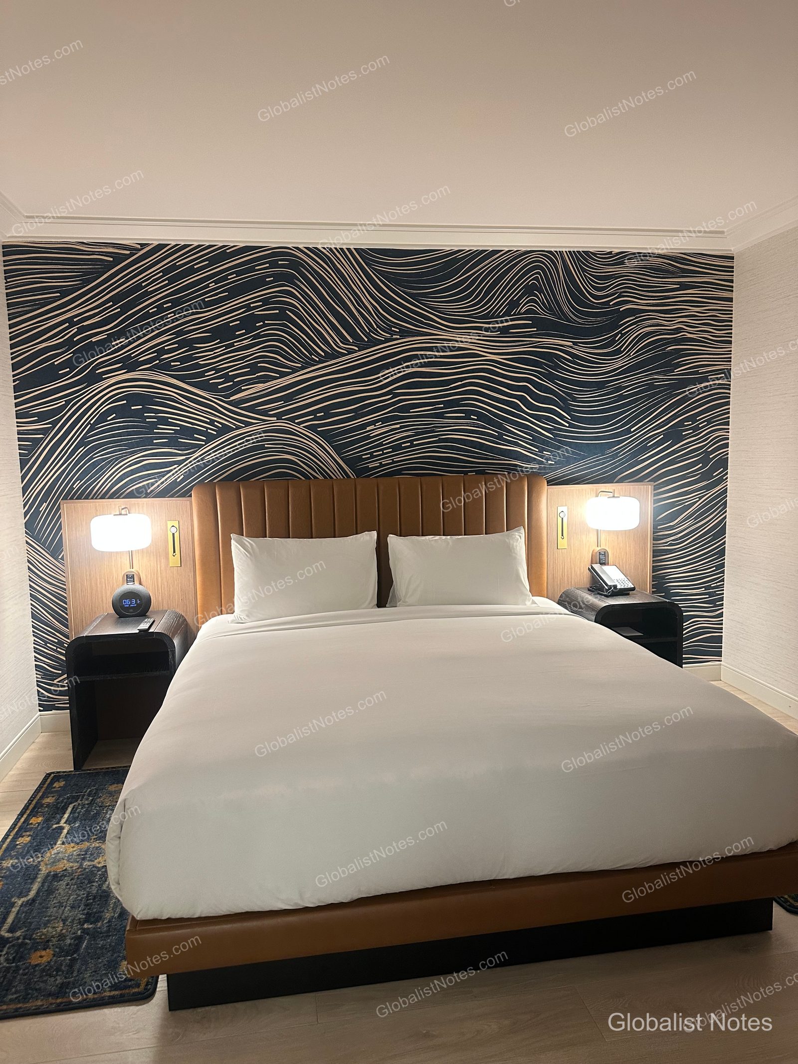 Hyatt Regency Irvine 一房套房臥室。棕色皮革床頭板後方為波浪紋壁紙，中央擺放一張配有床頭櫃與燈具的特大雙人床。