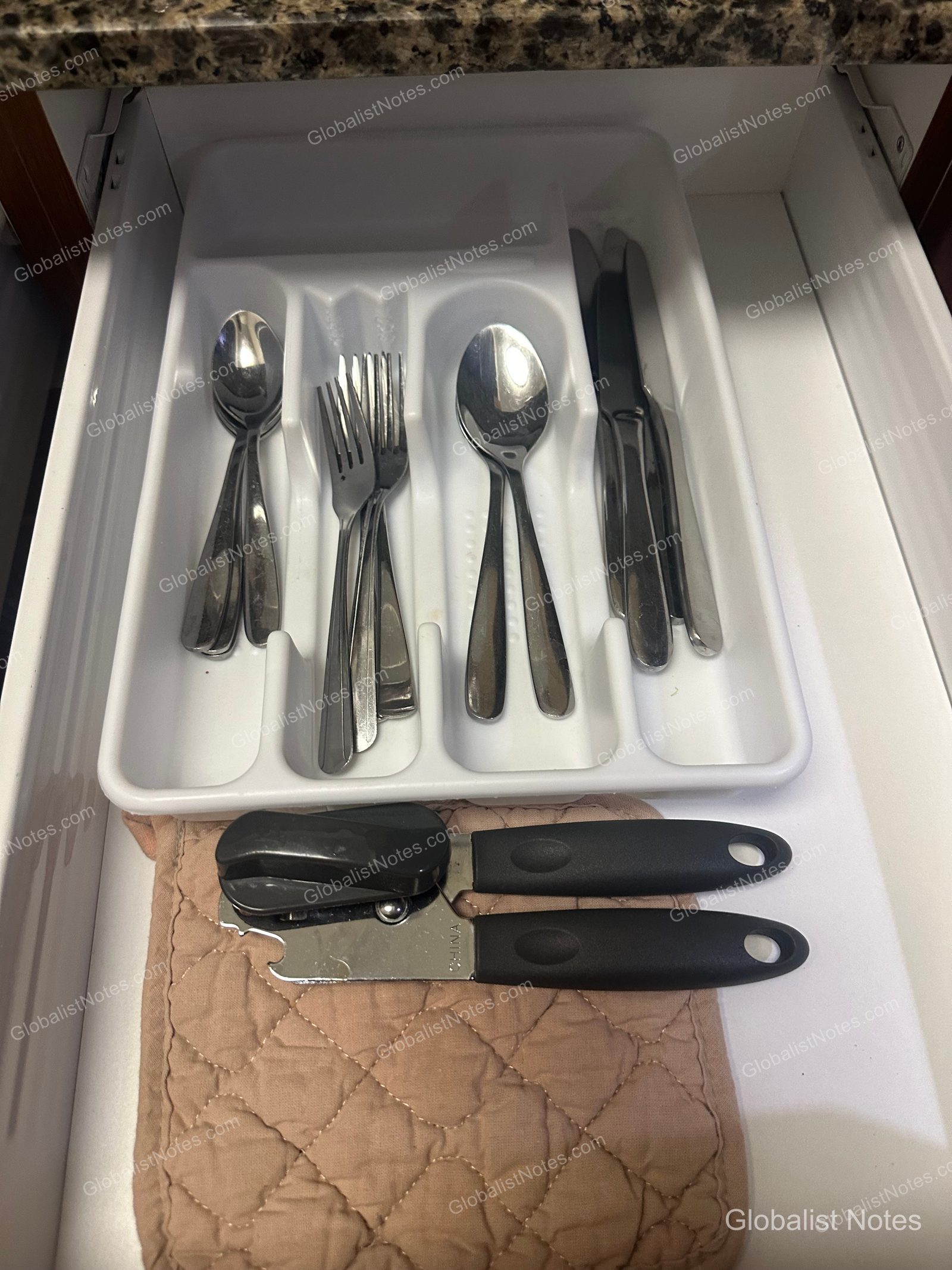 Hyatt House Scottsdale/Old Townのワンベッドルームスイートのキッチン引き出し。カトラリートレイにスプーン、フォーク、ナイフが収められ、下段には缶切りと鍋敷きがある。