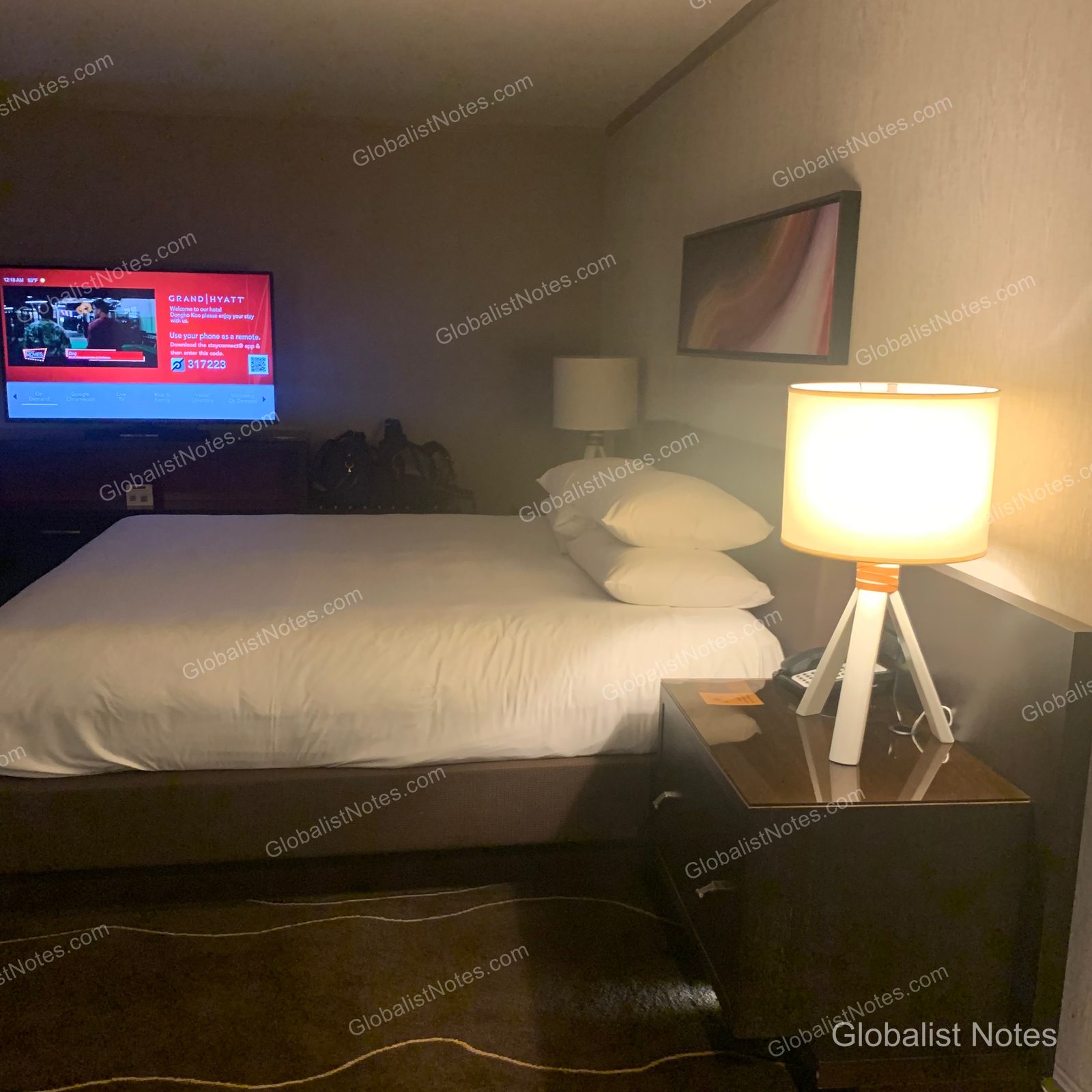 Grand Hyatt Denverの1キングベッド・コーナー・ルーム。キングベッド、サイドテーブル、壁掛けテレビが配され、テレビにはウェルカムメッセージが表示されている。