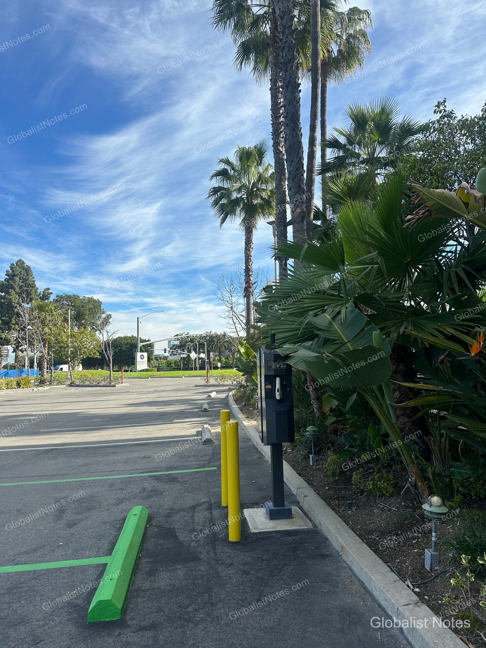 Hyatt Regency Newport Beach West 的戶外停車場。車位旁設有電動車充電樁，周邊種植棕櫚樹與綠色植栽，遠處可見飯店標誌。