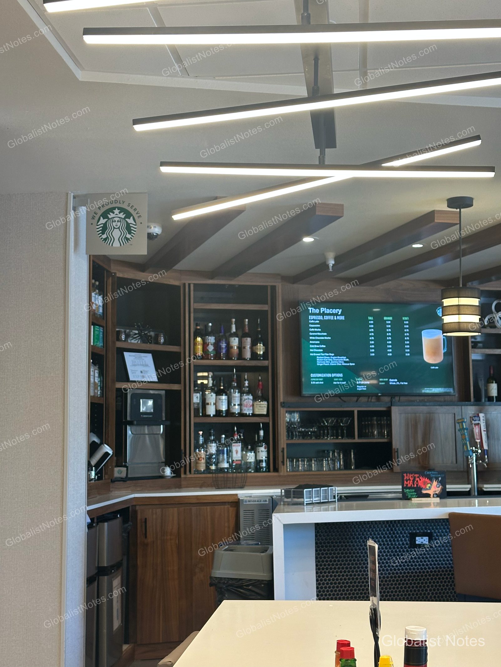 Hyatt Place Flagstaffの館内バー。デジタルスクリーンにはスターバックスのメニューが表示され、背後の棚にはボトルが並ぶ。天井にはモダンな照明が下がる。