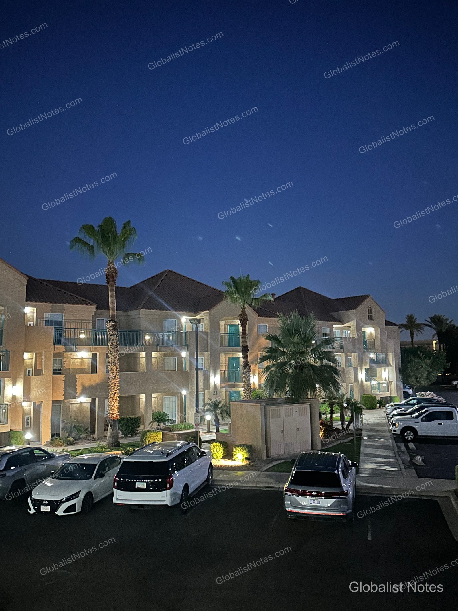 夜空の下、ライトアップされたHyatt House Scottsdale/Old Town。駐車場には車が並び、ヤシの木が植えられています。
