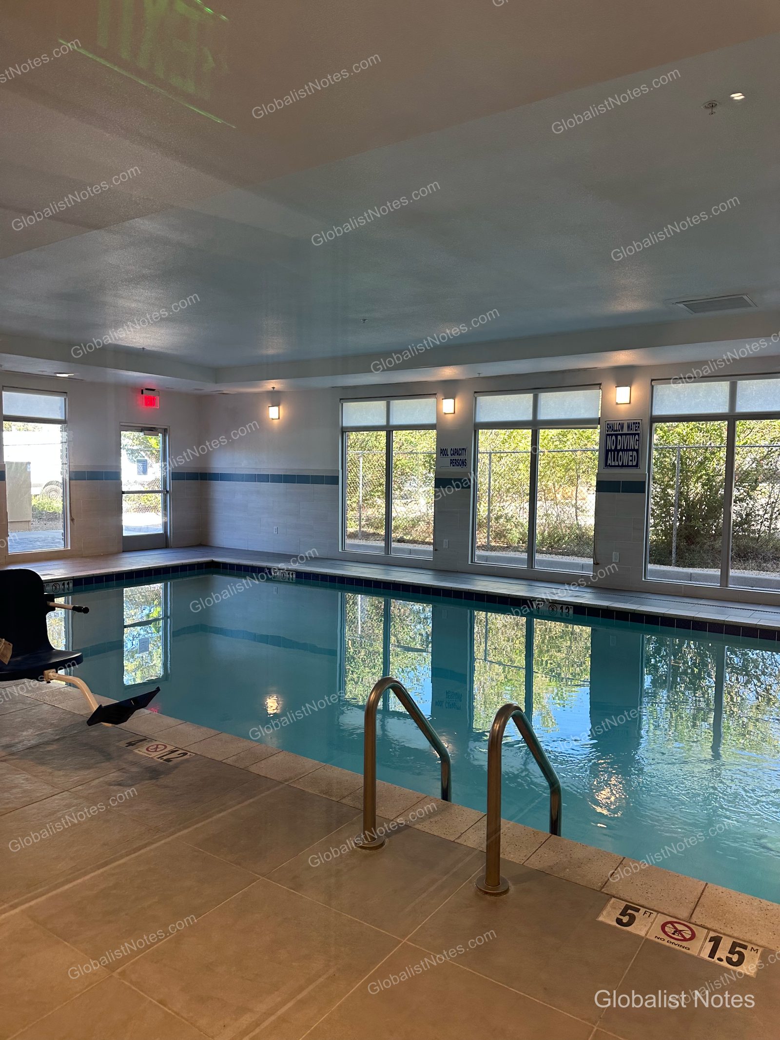 Hyatt Place Flagstaffの屋内プール。青いタイルが敷き詰められた長方形のプールで、金属製の梯子と昇降リフトが備わっています。大きな窓からは外の景色が望めます。