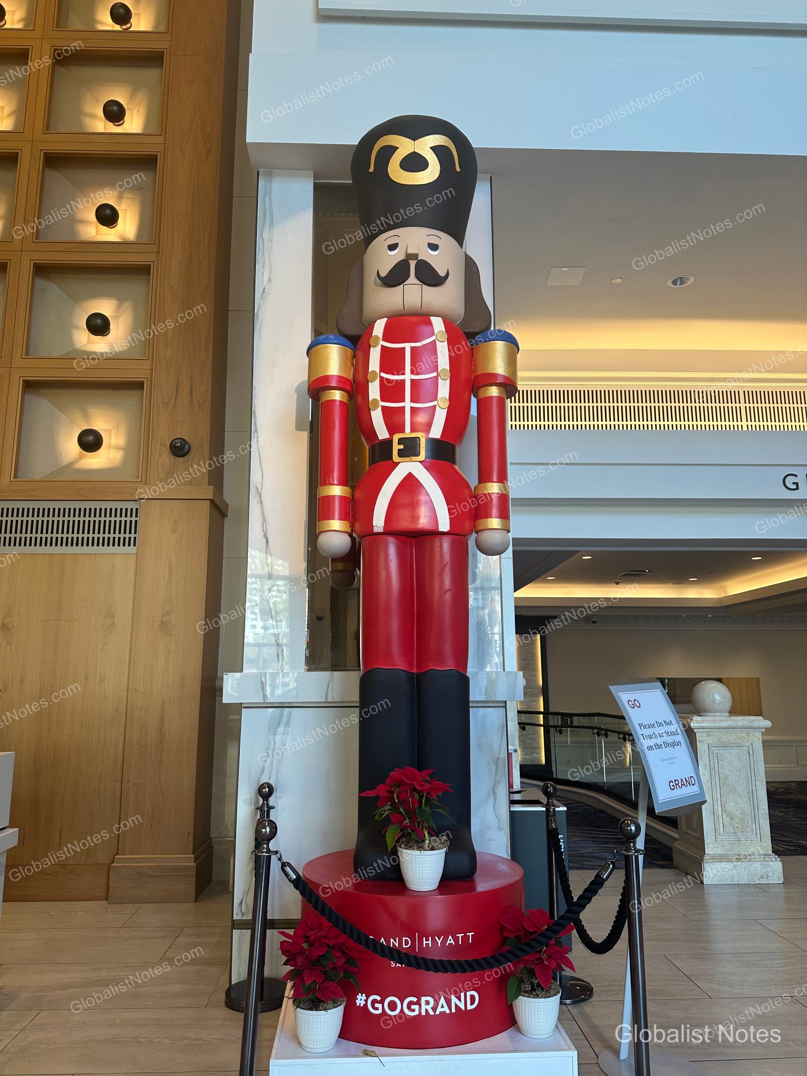 Manchester Grand Hyatt San Diego 大廳的大型胡桃鉗裝飾。身穿紅色制服的胡桃鉗人偶立於圓形底座，周圍環繞黑色圍欄與聖誕紅盆栽。
