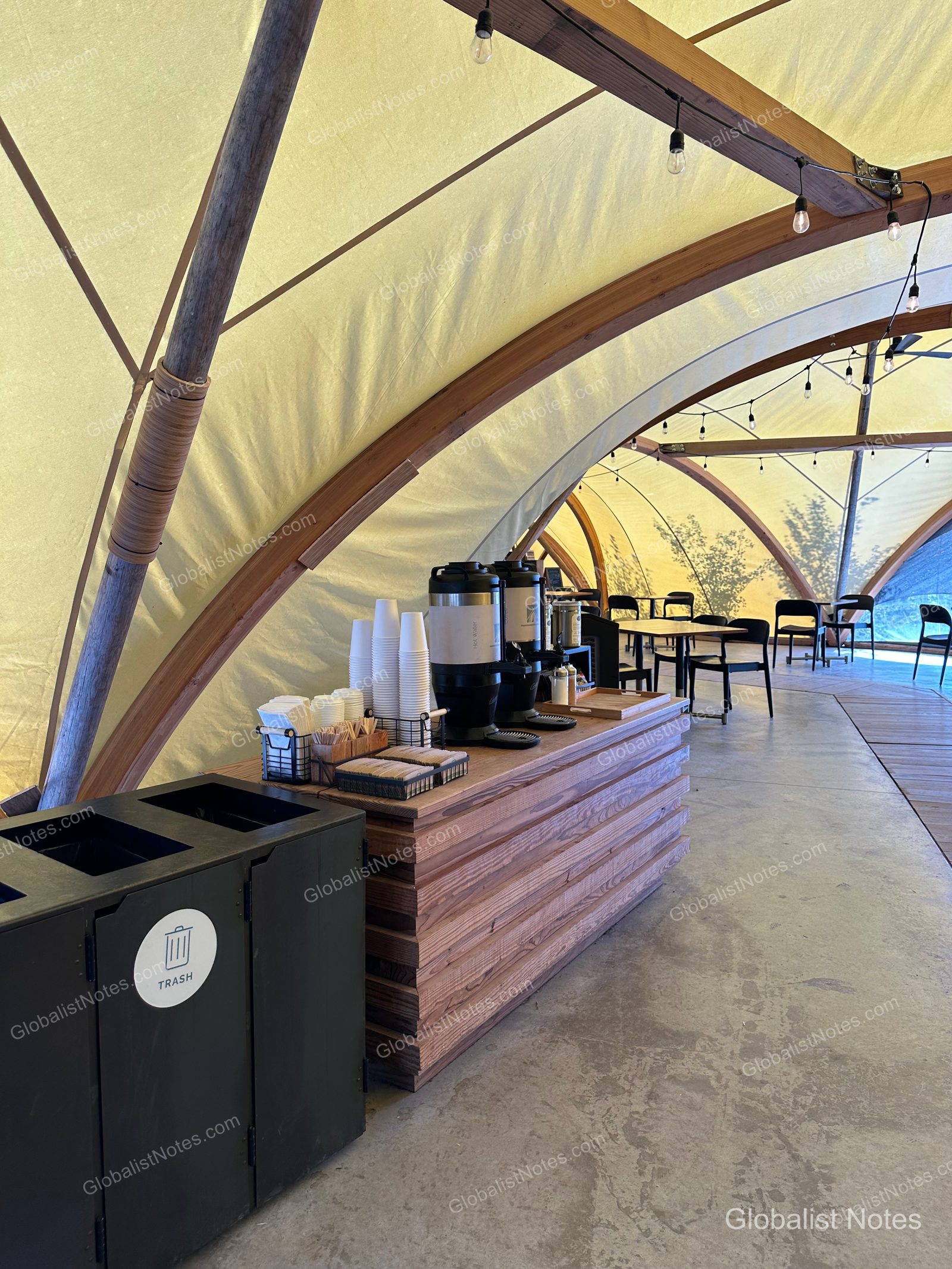 Under Canvas North Yellowstoneの大型テント内部。木製フレームとキャンバス地の天井の下にコーヒーコーナーがあり、奥には休憩スペースが広がっている。