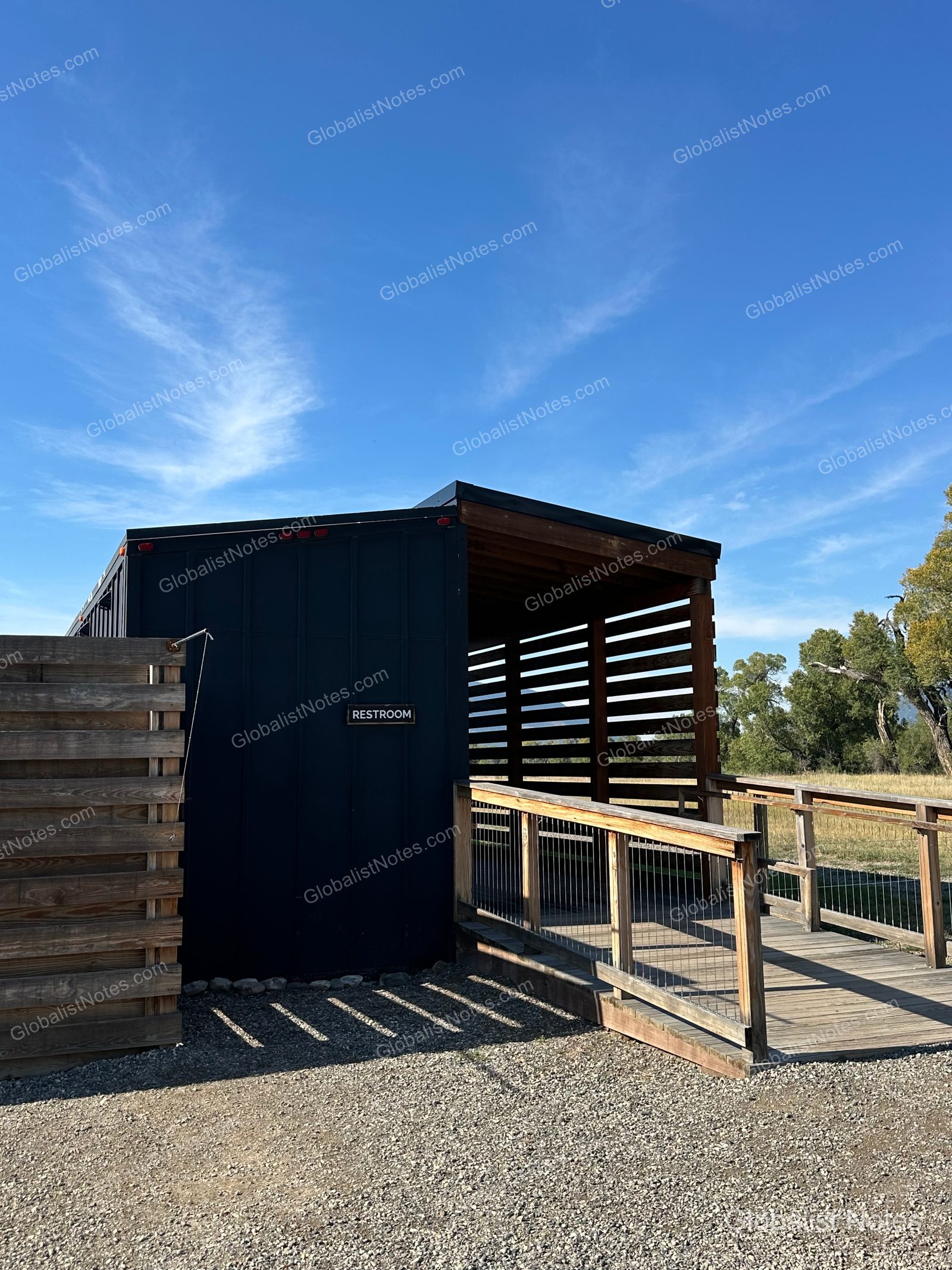 Under Canvas North Yellowstoneの共用トイレ棟。黒い外壁に「RESTROOM」の看板が掲げられ、木製のスロープと柵が設置されている。