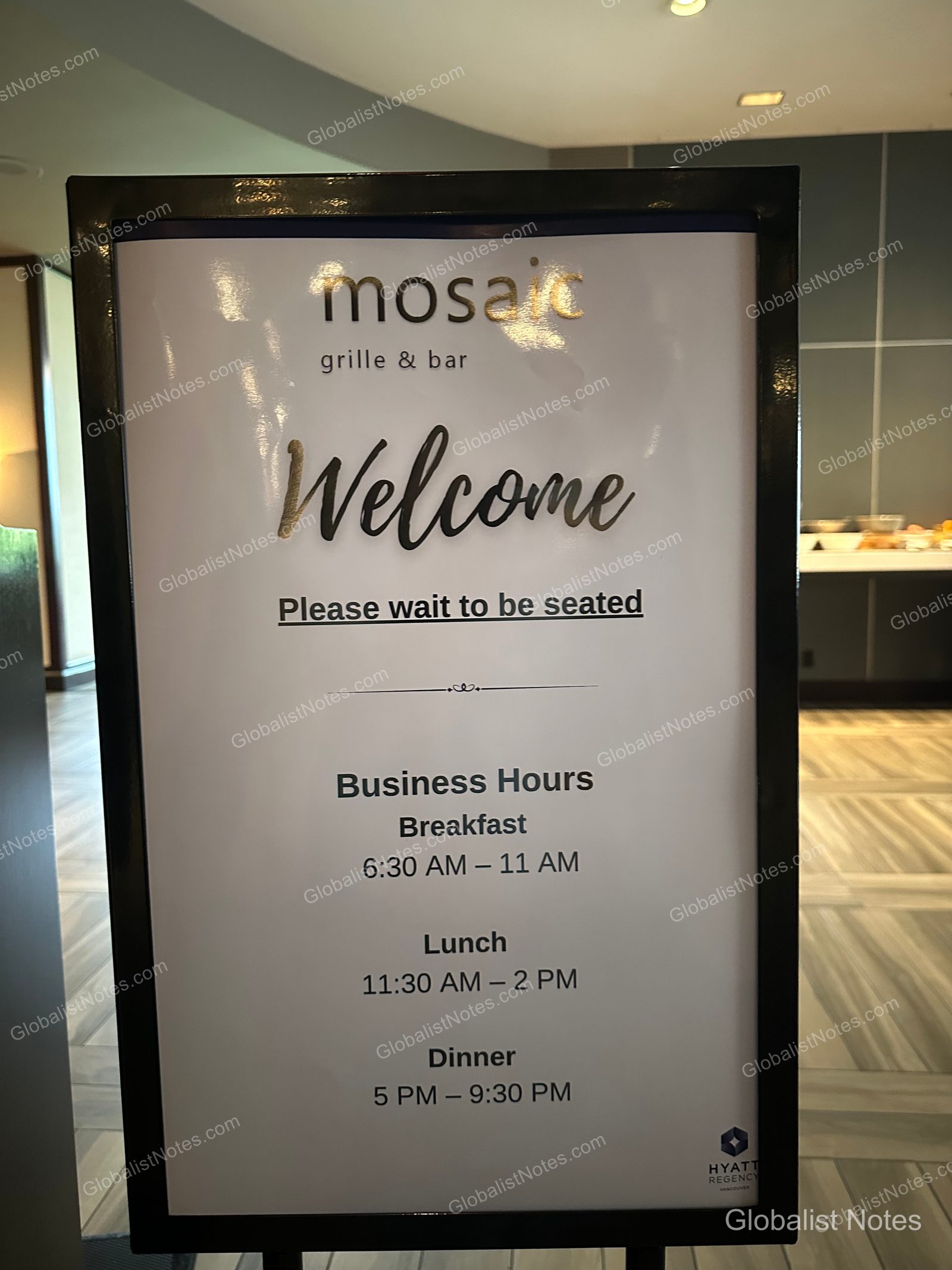 A black-framed sign at the entrance of Mosaic Grille & Bar at Hyatt Regency Vancouver, displaying the restaurant name at the top and instructions to wait to be seated, along with detailed operating hours for breakfast, lunch, and dinner.