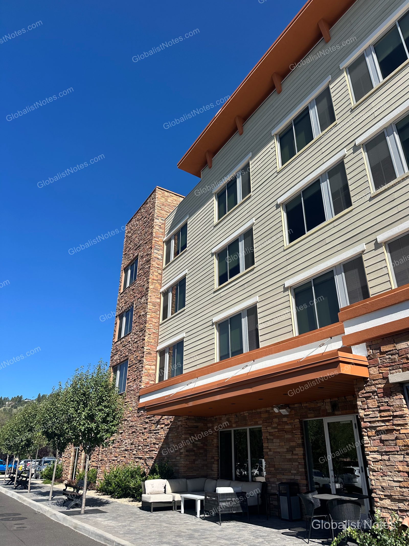 フラッグスタッフにあるHyatt Placeの外観。ベージュのサイディングと天然石が調和した建物で、入り口前のテラスには屋外ソファとテーブルが配置されています。