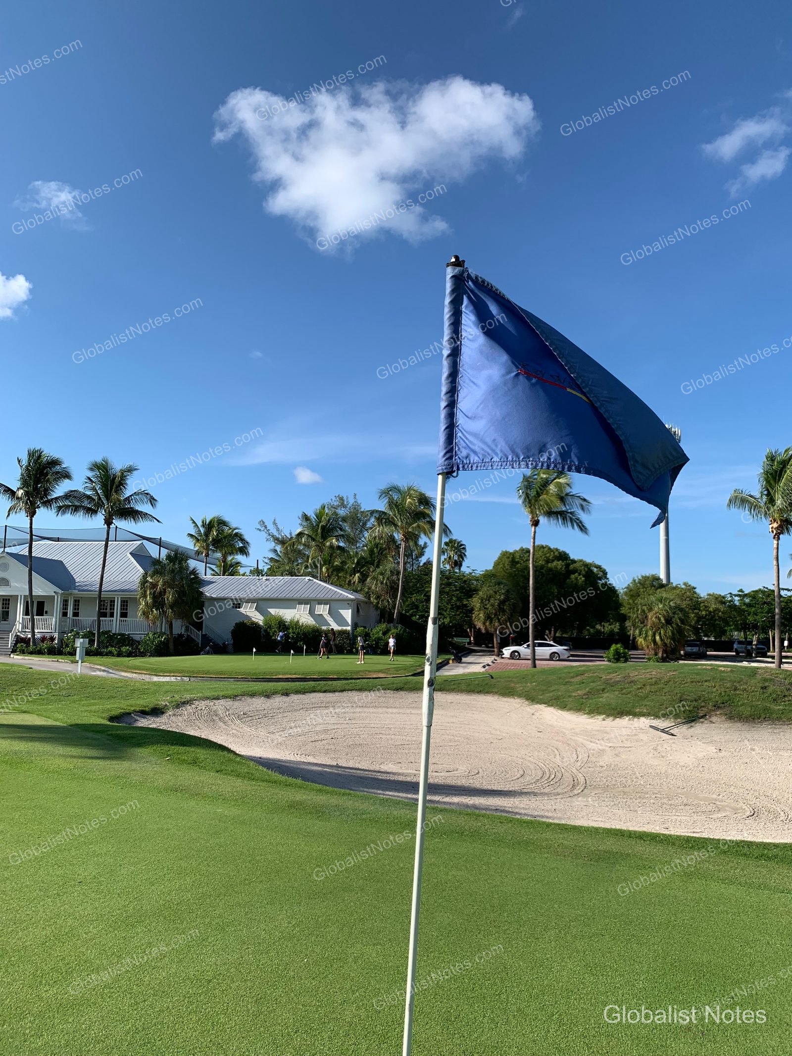 Hyatt Vacation Club at Sunset Harbor近郊のゴルフコース。青々とした芝生とバンカー、ピンが立つグリーンの背後にヤシの木と白い建物が並び、晴天の下でプレーを楽しむ人々の姿がある。