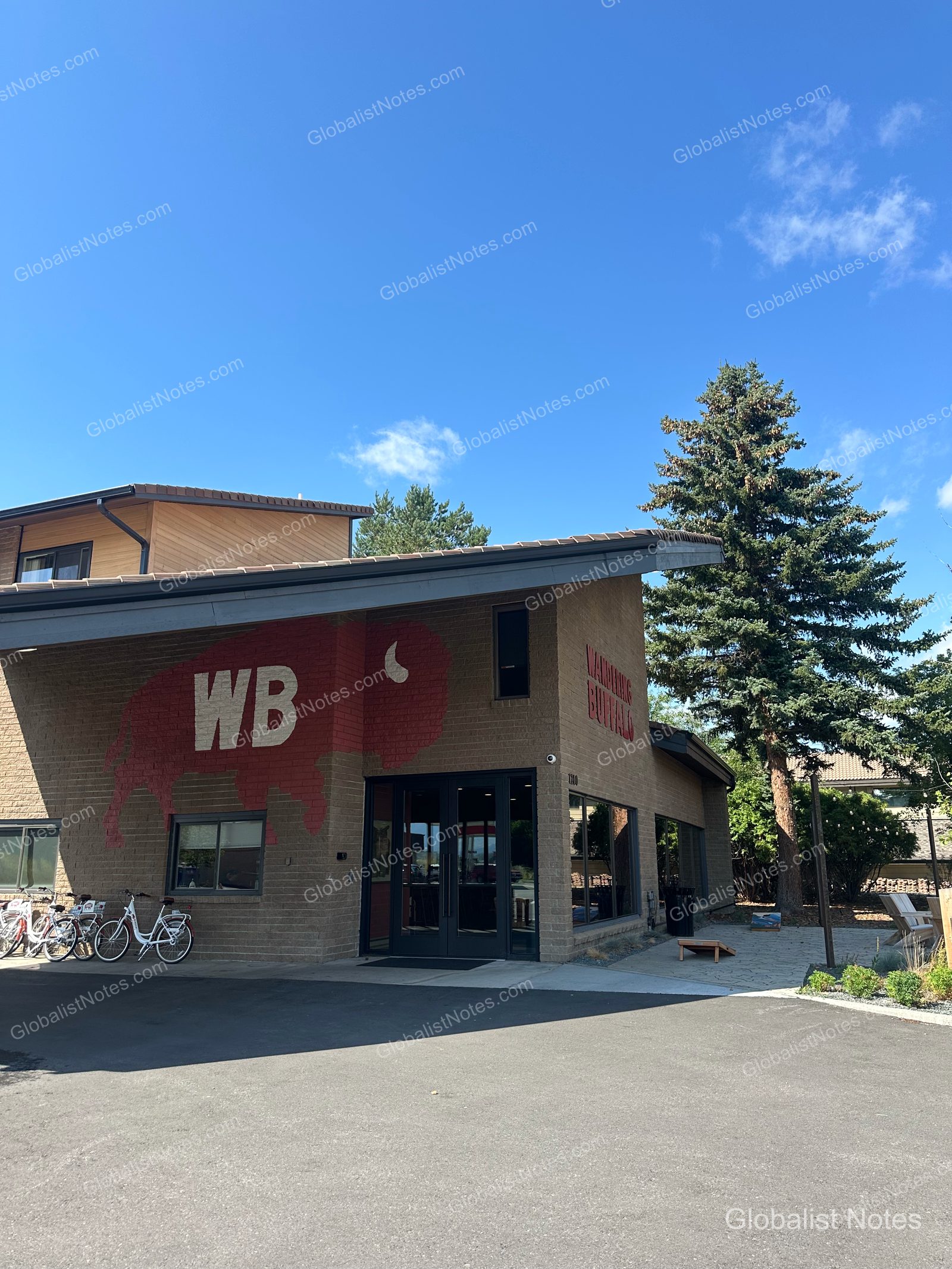 米国ボーズマンのWandering Buffaloの外観。レンガ壁に赤いバッファローのシルエットとWBロゴが描かれ、建物の前には宿泊客用の自転車が置かれています。