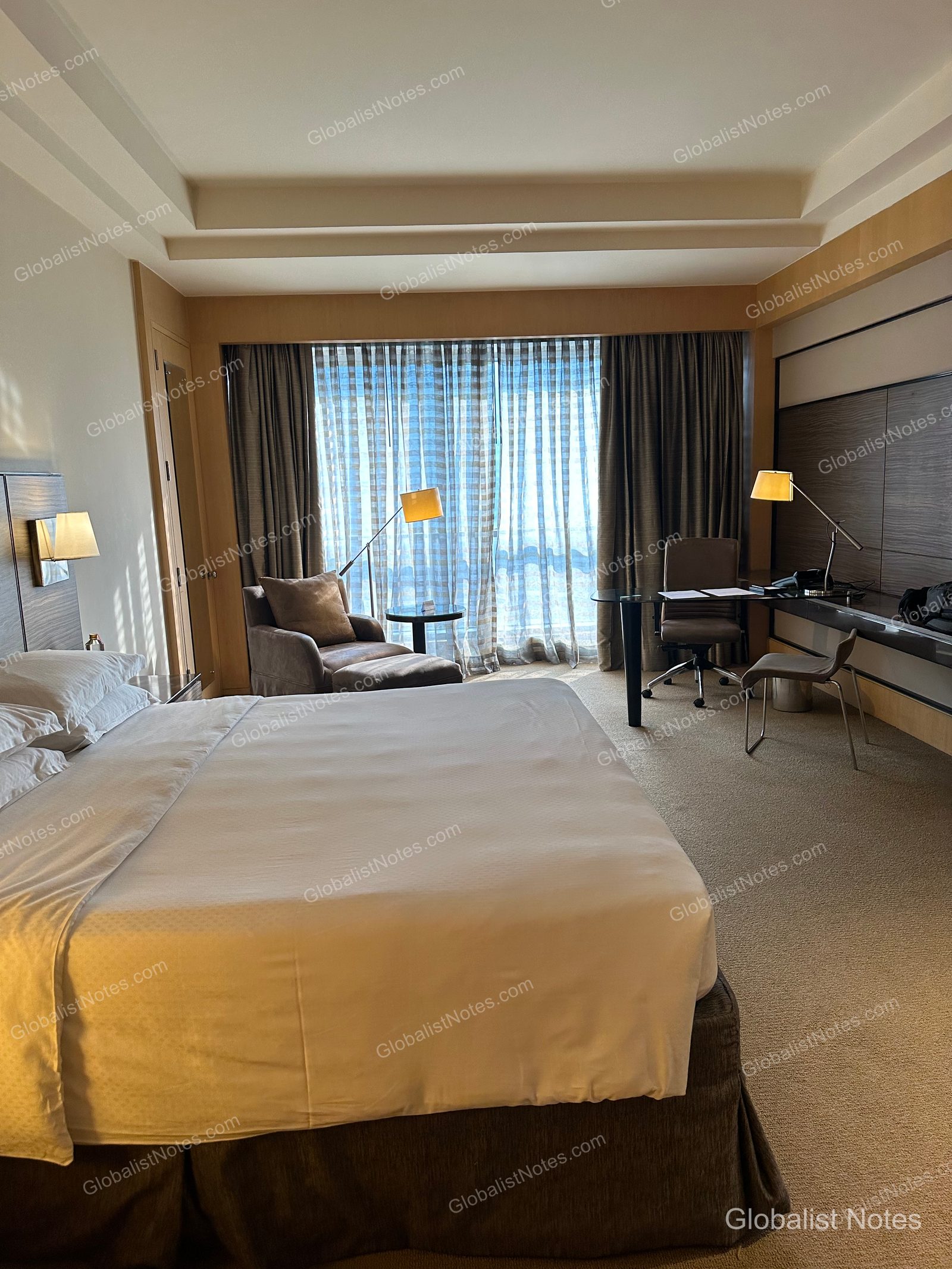 The interior of a Veranda Suite King at Grand Hyatt Mumbai, showing a king bed with white linens, a single-seat sofa, and a desk positioned by the window.