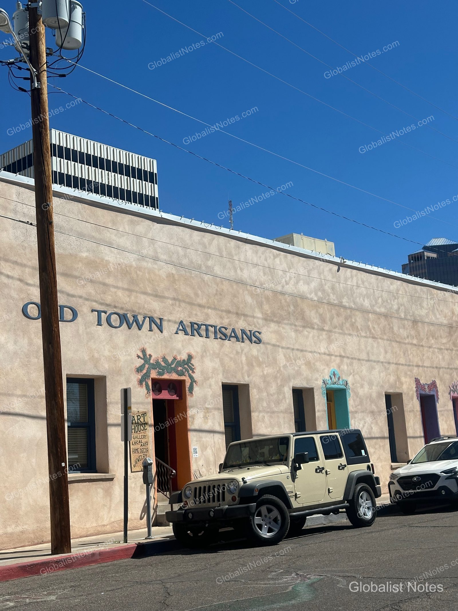 Exterior of the Old Town Artisans building near the San Antonio River Walk, featuring a beige wall with 'OLD TOWN ARTISANS' signage and a Jeep parked in front.