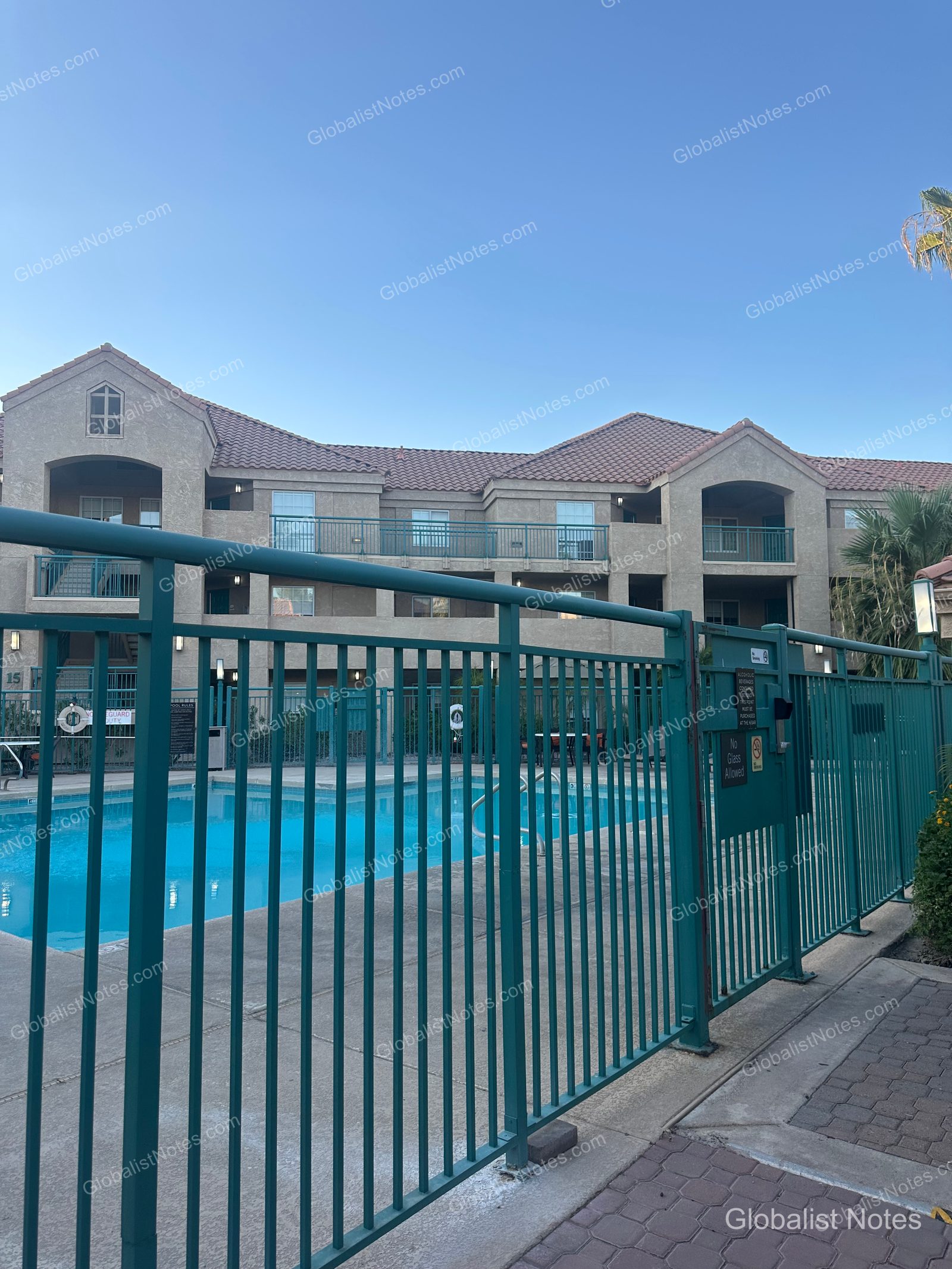 Hyatt House Scottsdale/Old Townの屋外プール。青緑色のフェンスに囲まれ、背後には3階建ての客室棟が並んでいます。