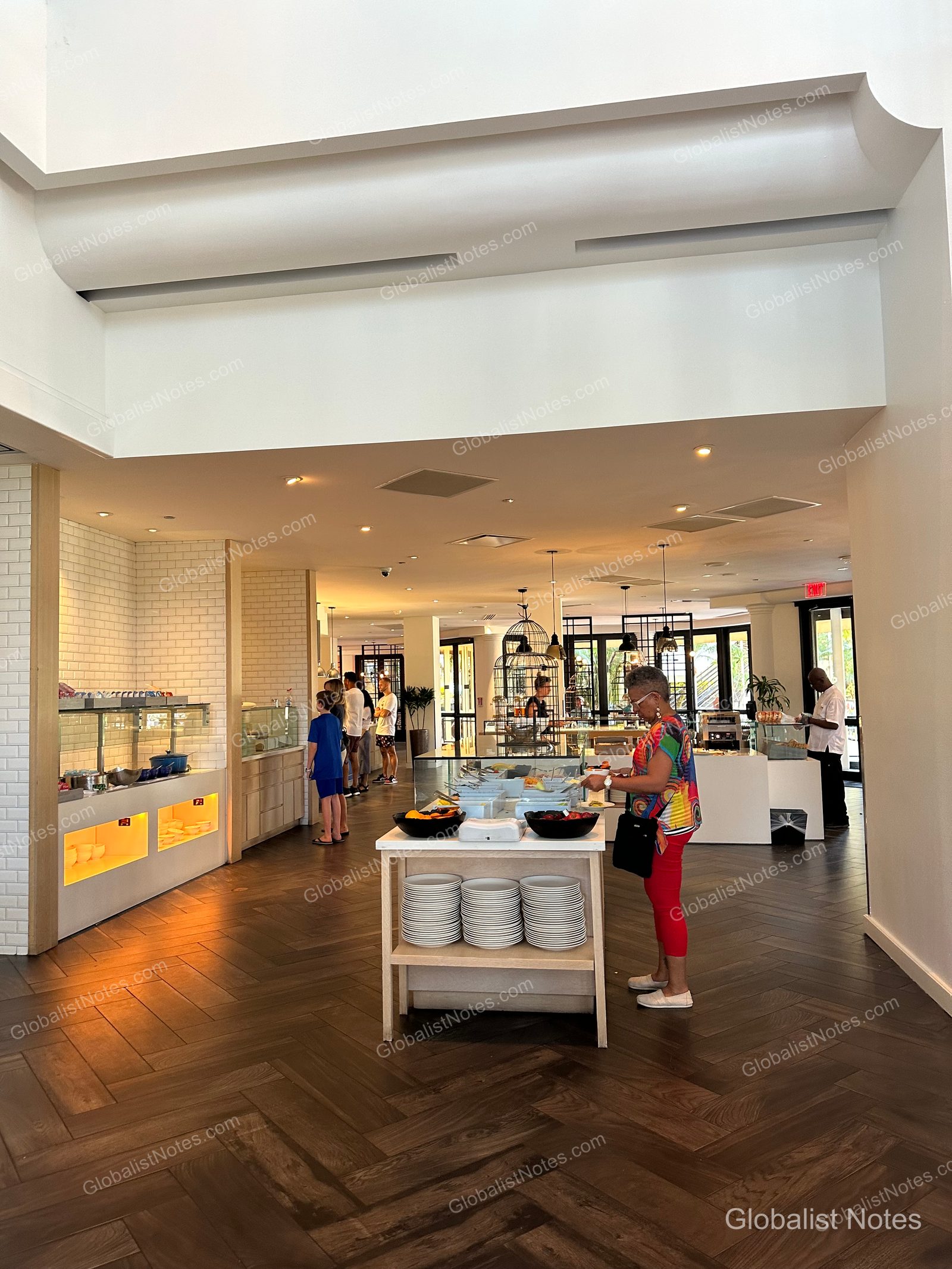 The bright and open breakfast buffet area at Hyatt Regency Grand Cypress in Orlando, with stacks of plates on a central island and guests selecting food.