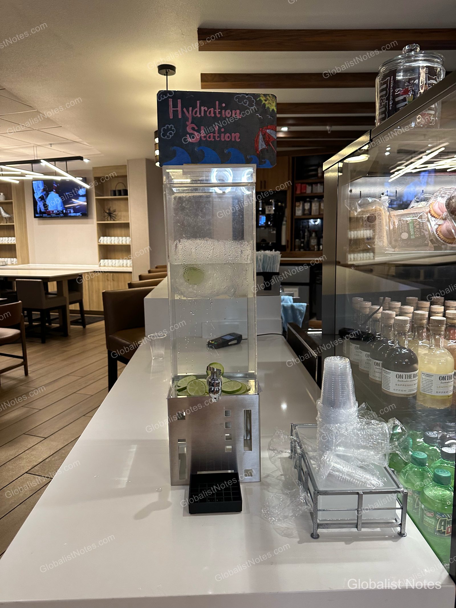 Hyatt Place Flagstaffのロビーにある給水ステーション。ライム入りの冷水が入ったディスペンサーと、その横に紙コップやドリンク類が並ぶショーケース。