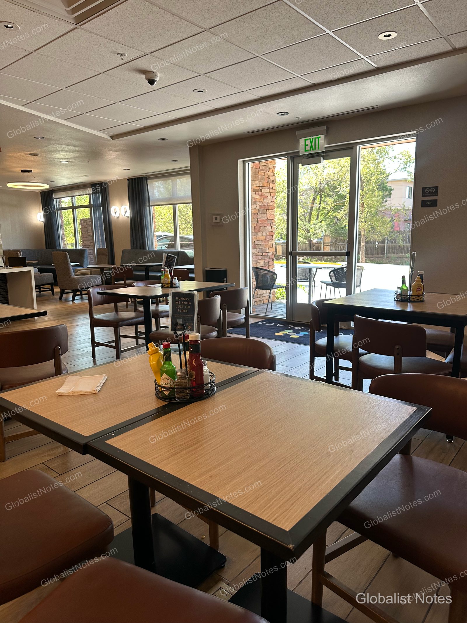 Hyatt Place Flagstaffの朝食エリア。正方形のテーブルとブラウンの椅子が整然と並び、大きな窓から外の景色が広がります。