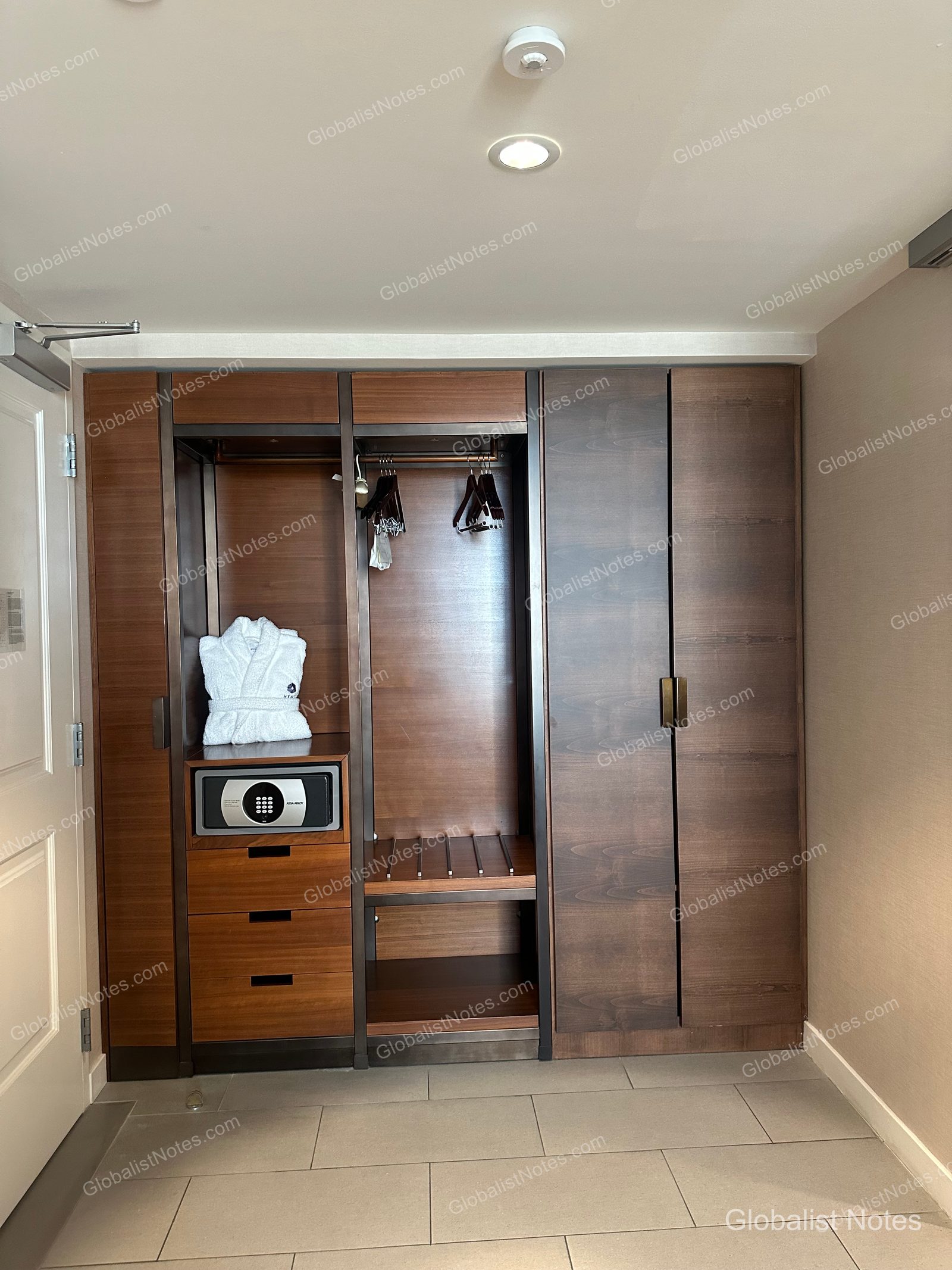 Hyatt Regency Newport Beach West 標準大床房內的嵌入式衣櫃。左側有白色浴袍、保險箱與抽屜櫃，中央為衣架與行李架，右側為封閉式櫃門。