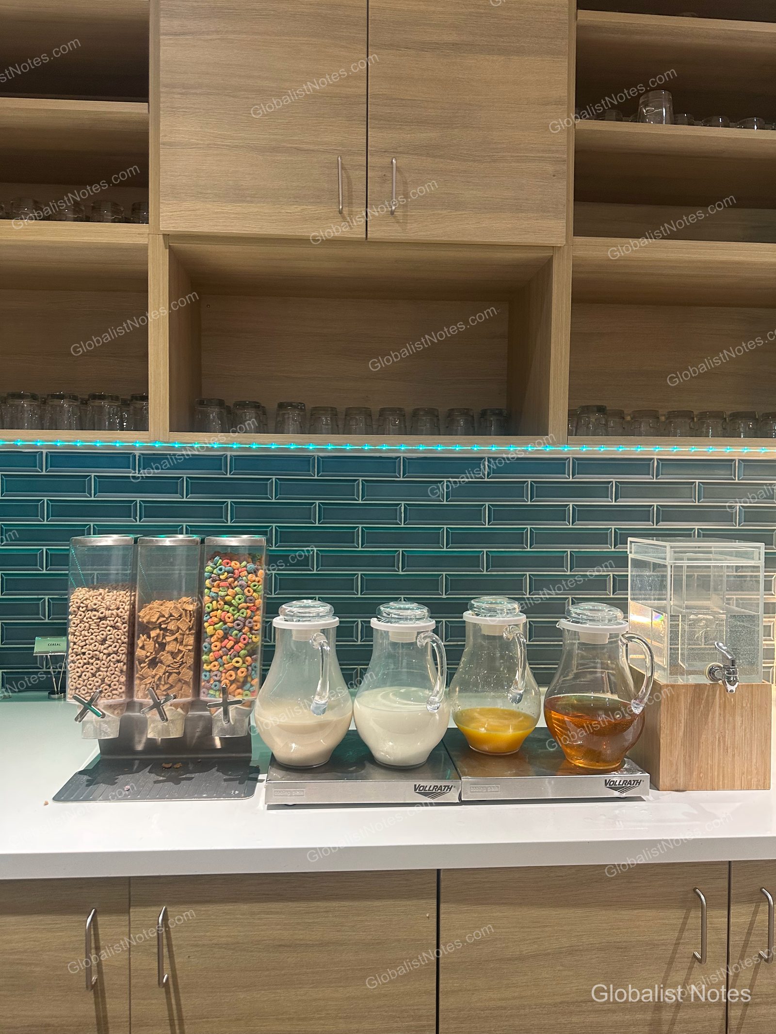 Hyatt Place Flagstaffの朝食コーナー。3種類のシリアルディスペンサーと、牛乳、ジュース、紅茶の入ったガラス製ジャグが並び、背景にはターコイズブルーのタイル壁と木製の棚が見える。