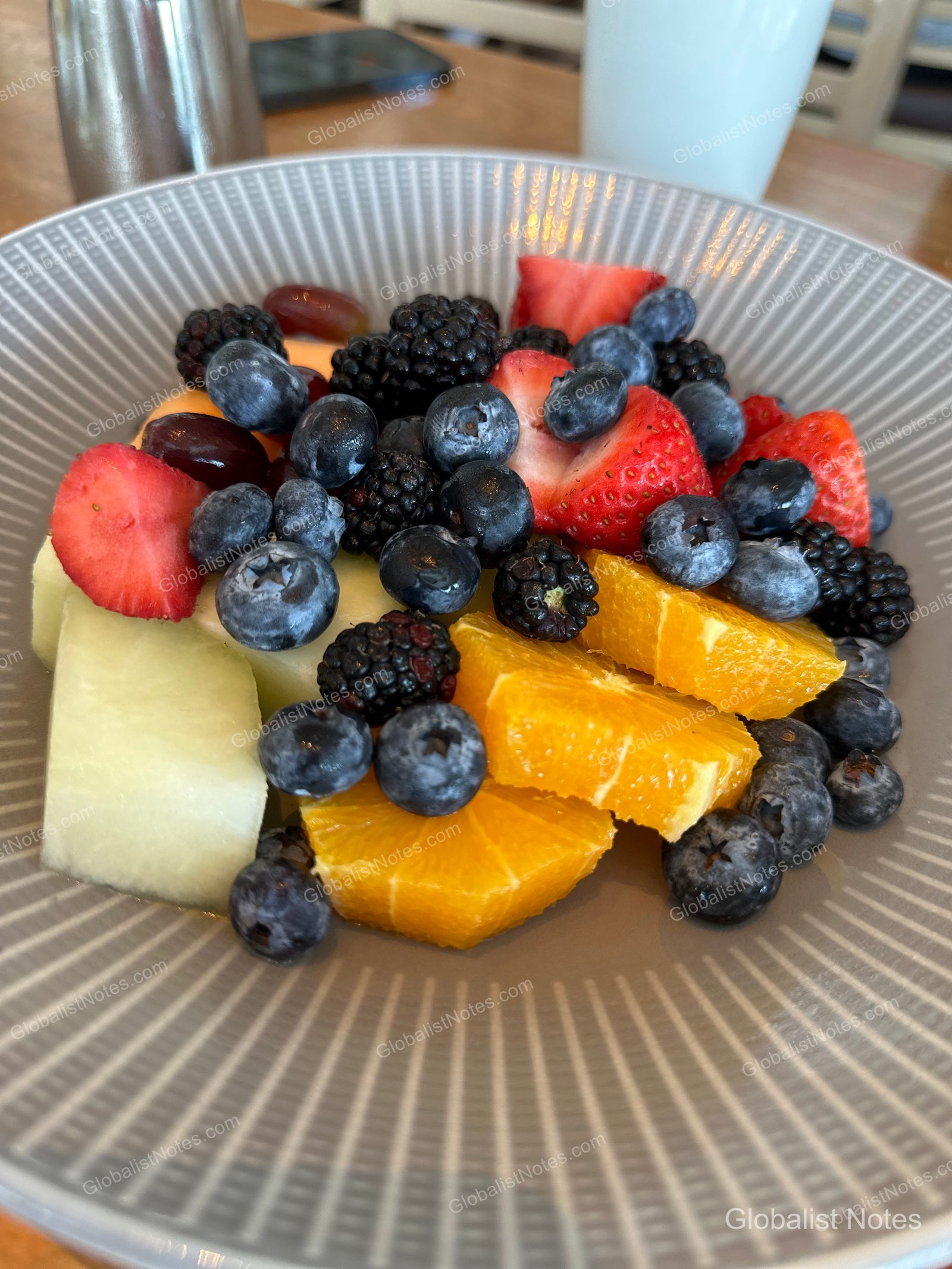 A fruit plate from the Hyatt Regency Grand Cypress breakfast buffet, featuring melon, orange, strawberries, blueberries, and blackberries in a light gray striped bowl.