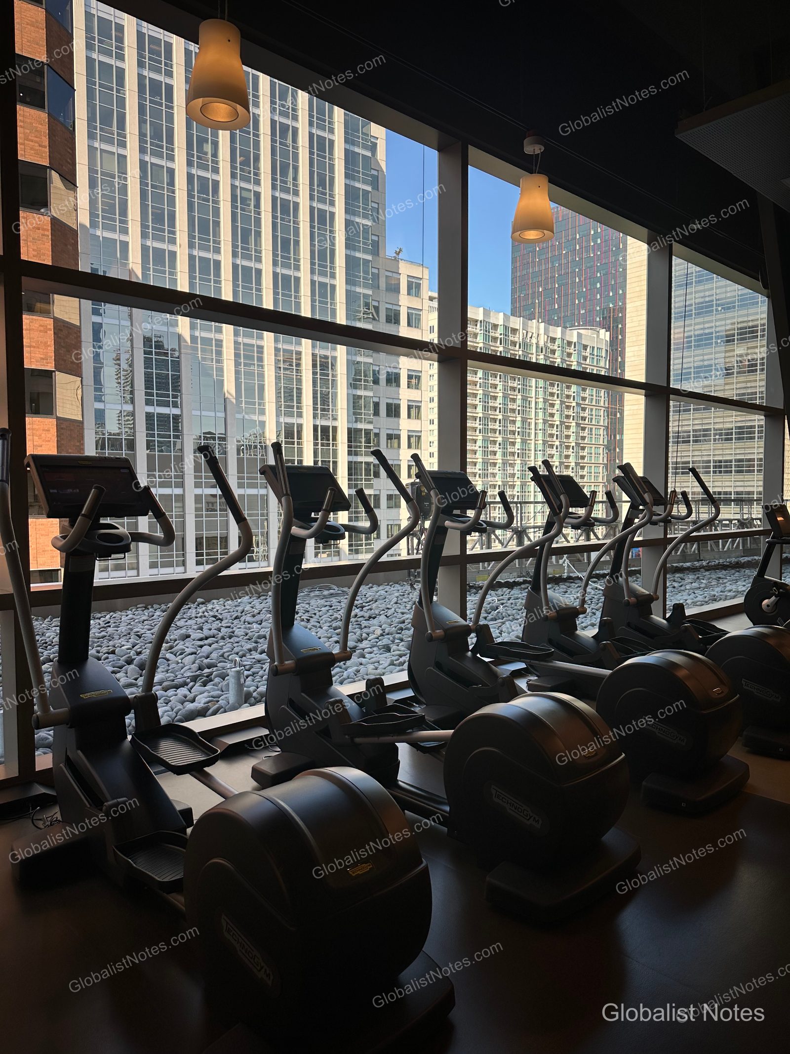 A row of elliptical machines inside the Hyatt Regency Seattle fitness center, with floor-to-ceiling windows overlooking the downtown Seattle skyline.