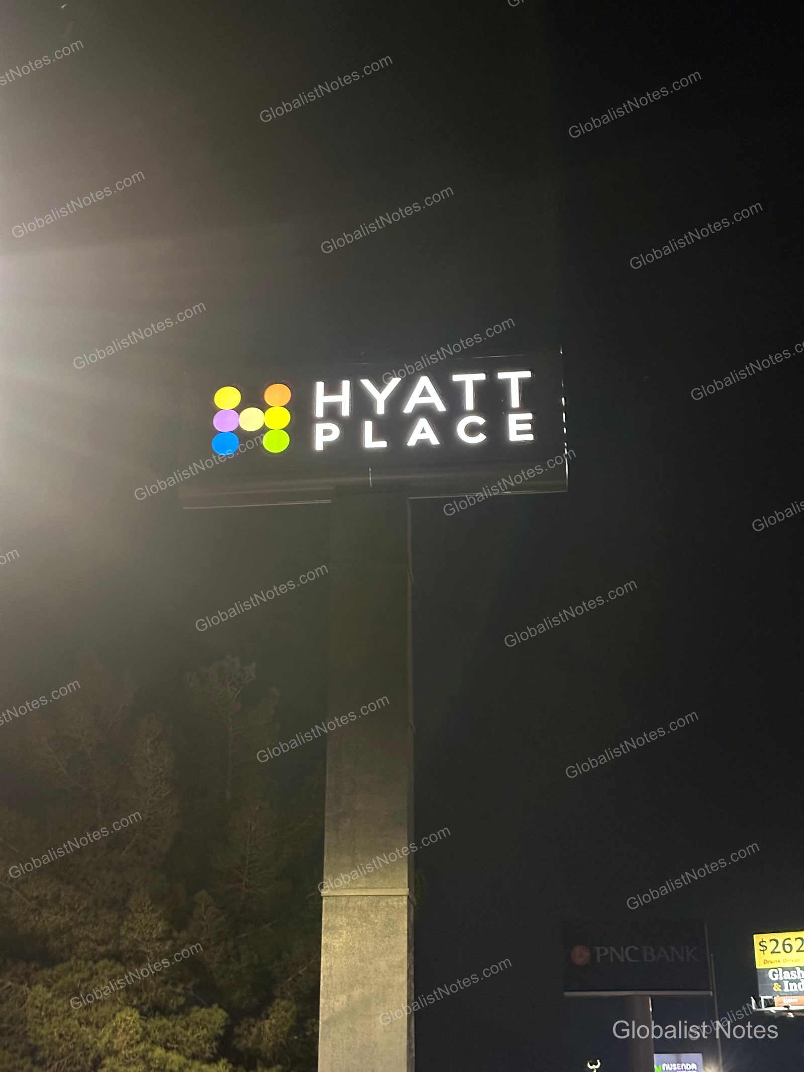 夜色中，路邊豎立著印有 Hyatt Place 標誌的高聳立柱招牌，在黑暗中發出明亮光芒。