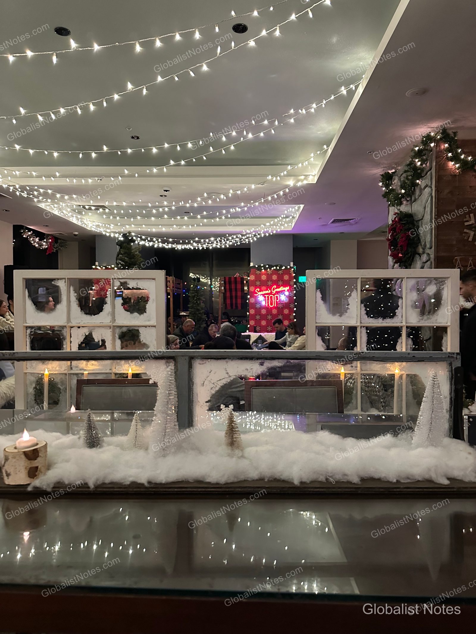 Manchester Grand Hyatt San Diego 室內空間，天花板懸掛華麗燈飾，桌上擺放人造雪、迷你聖誕樹及窗框裝飾，營造出聖誕氛圍。