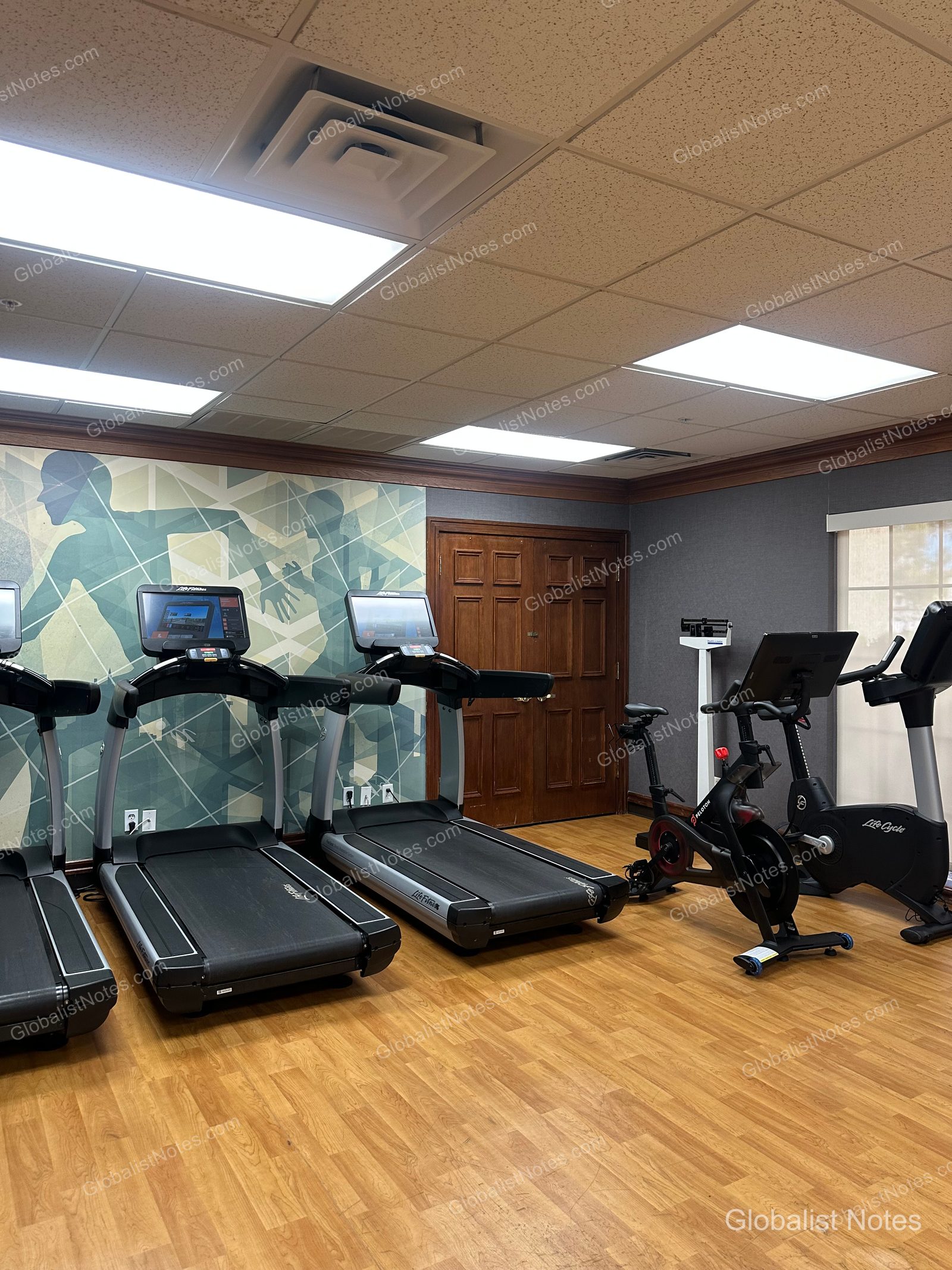 Hyatt House Scottsdale/Old Townのフィットネスセンター。明るい空間にLife Fitnessのトレッドミル2台、Pelotonバイク、インドアバイクが並び、壁面には幾何学模様のアートが施されています。